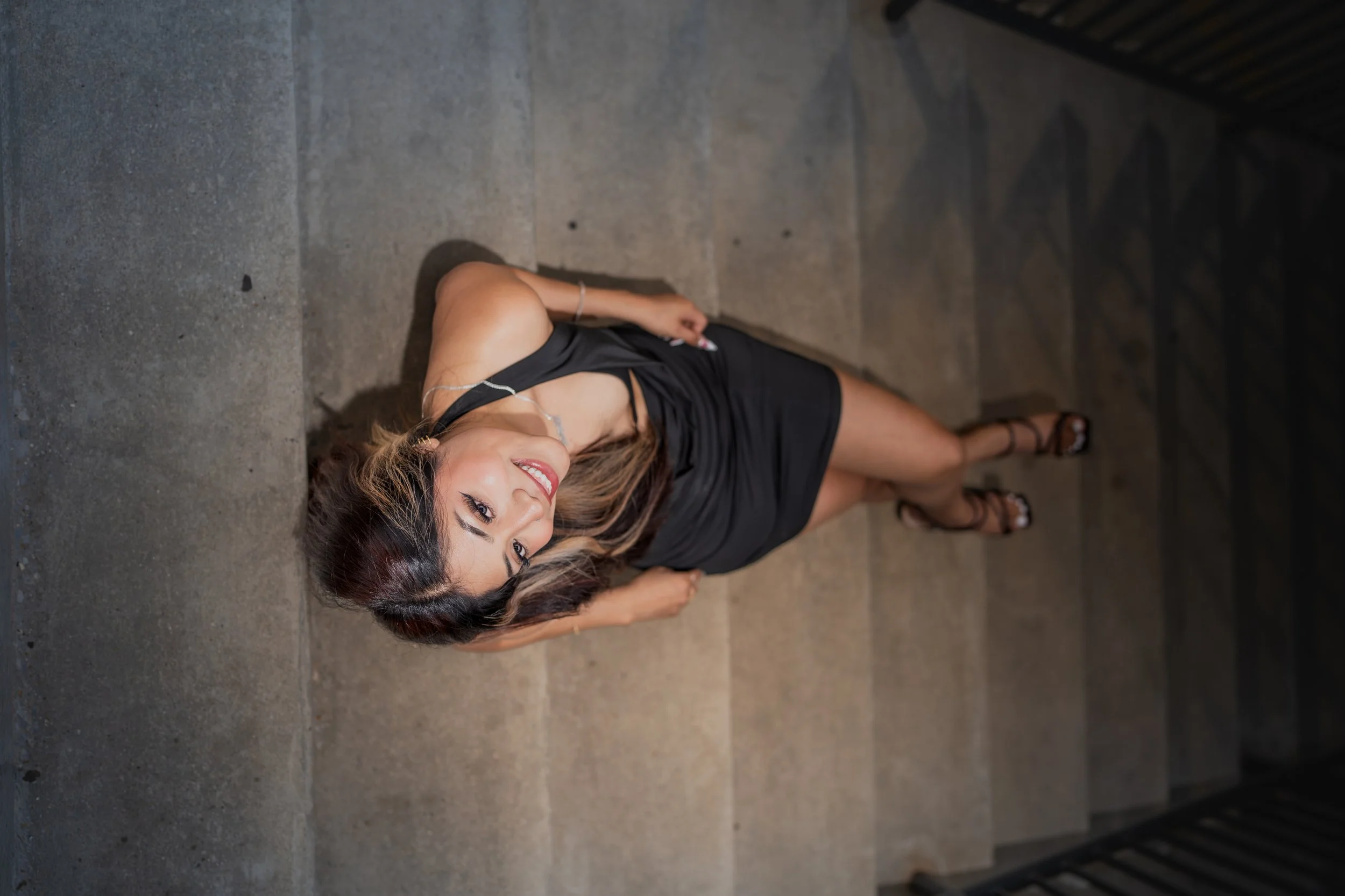 young woman posing on stairway, looking up at camera, aesthetic style