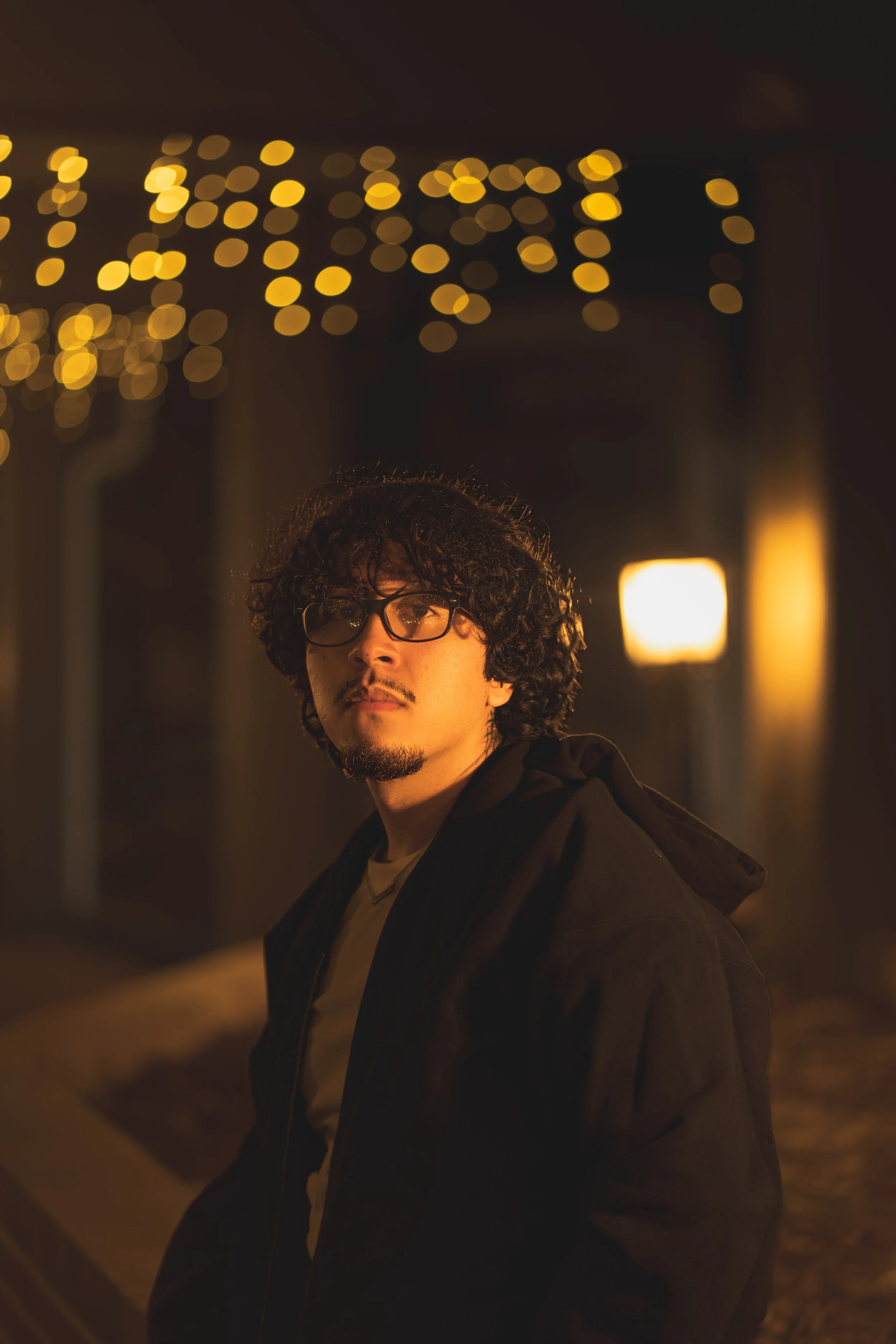 young man with curly hair posing outside coffee shop, casual look