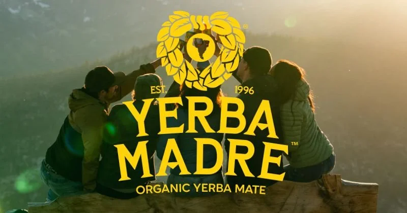 Five people sitting together outdoors during sunset, with a logo and text overlay from Yerba Madre, an organic yerba mate brand.