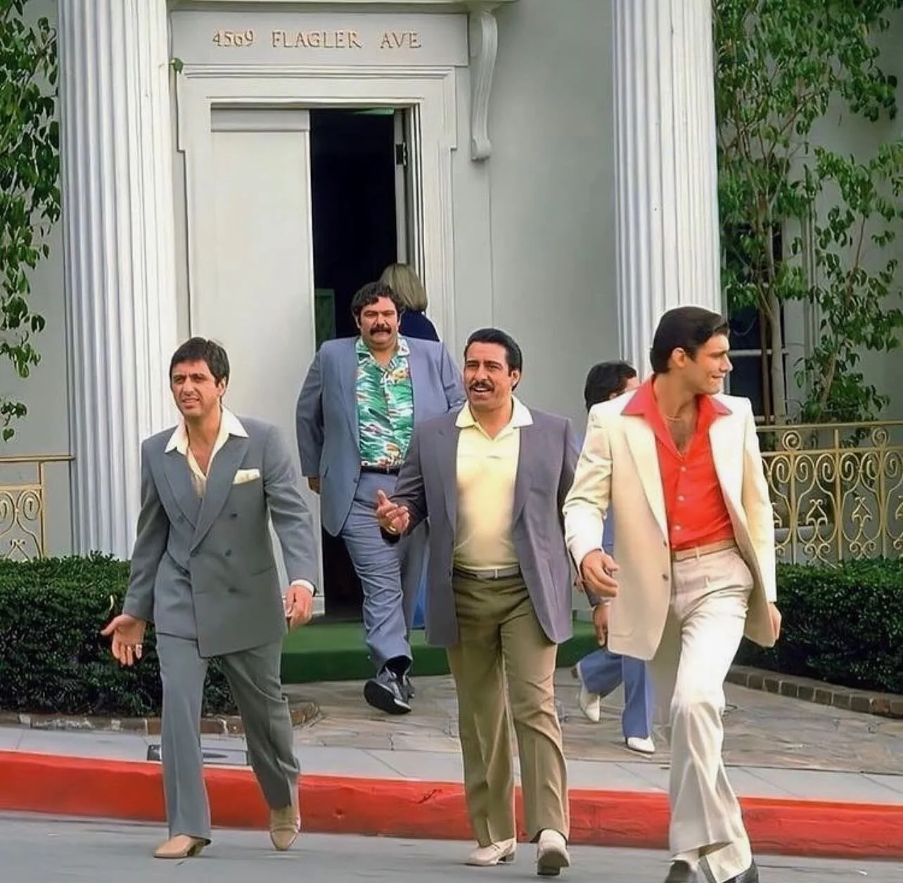 A group of men dressed in colorful suits walking down the street in front of a building with a sign that reads '4505 W Flagger Ave'.