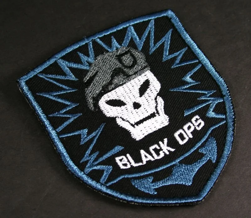 A black embroidered patch featuring a skull with a police cap and sunglasses, with blue lightning bolts around it and the words "BLACK OPS" at the bottom.