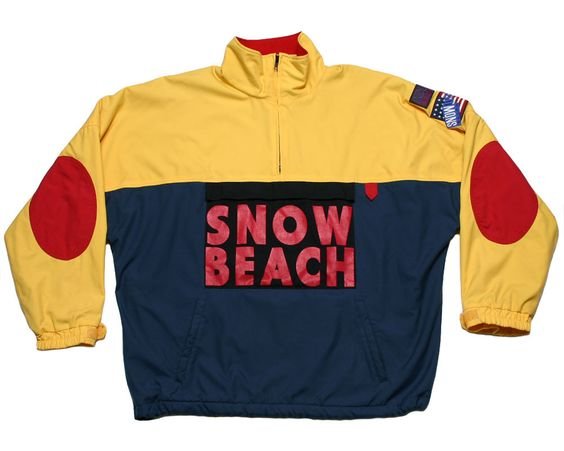 Colorful jacket with yellow, red, and navy blue sections, featuring patches and the words 'SNOW BEACH' on the front.