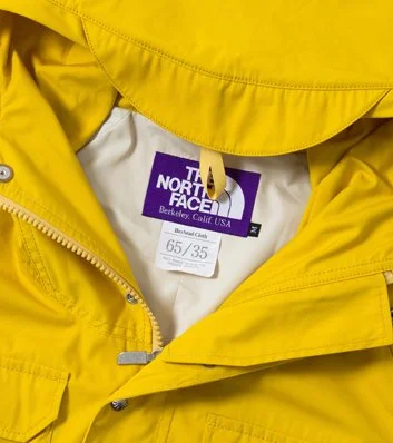 A yellow The North Face jacket with a white and purple label inside it.