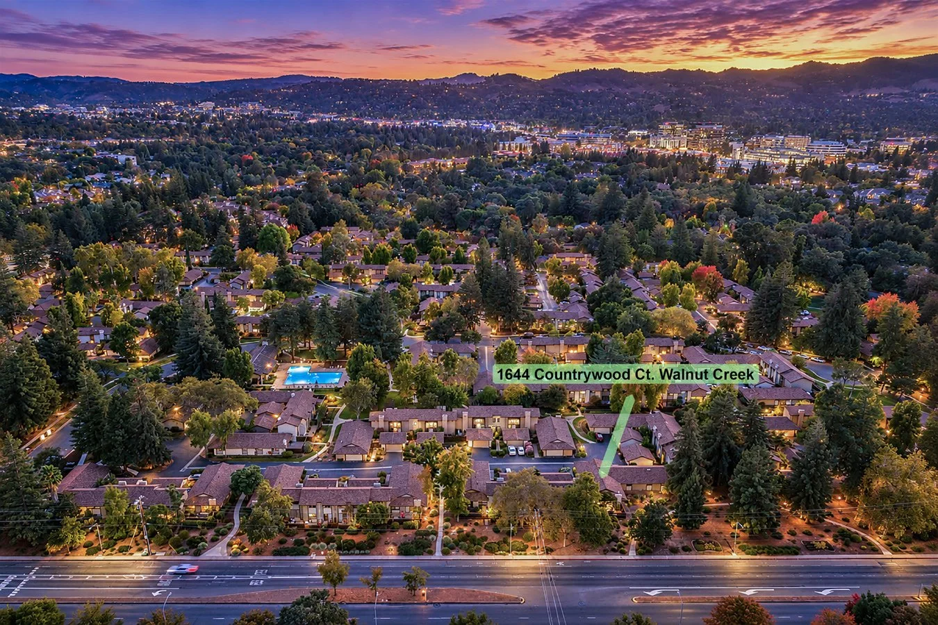 Aerial view of a residential neighborhood at dusk with trees, houses, a swimming pool, and a street, with city lights and hills in the background. A label indicates 1644 Countrywood Ct. Walnut Creek.