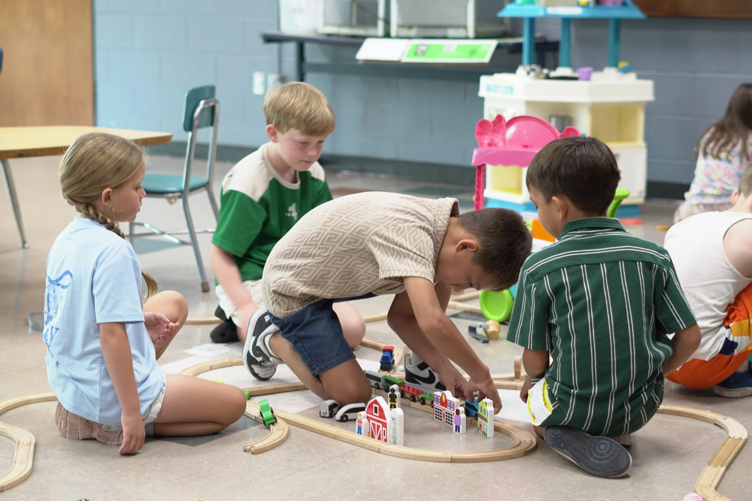 Children playing together with toy trains and buildings during a church kids activity.