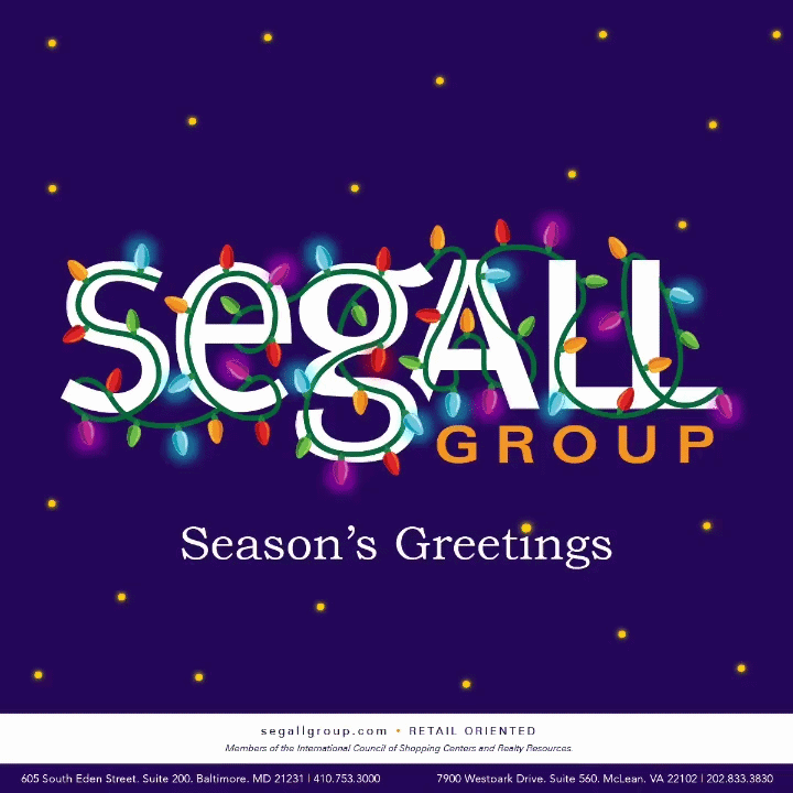 Christmas lights spelling out 'Segall Group' with greeting 'Season's Greetings' against a dark blue background with small yellow dots.