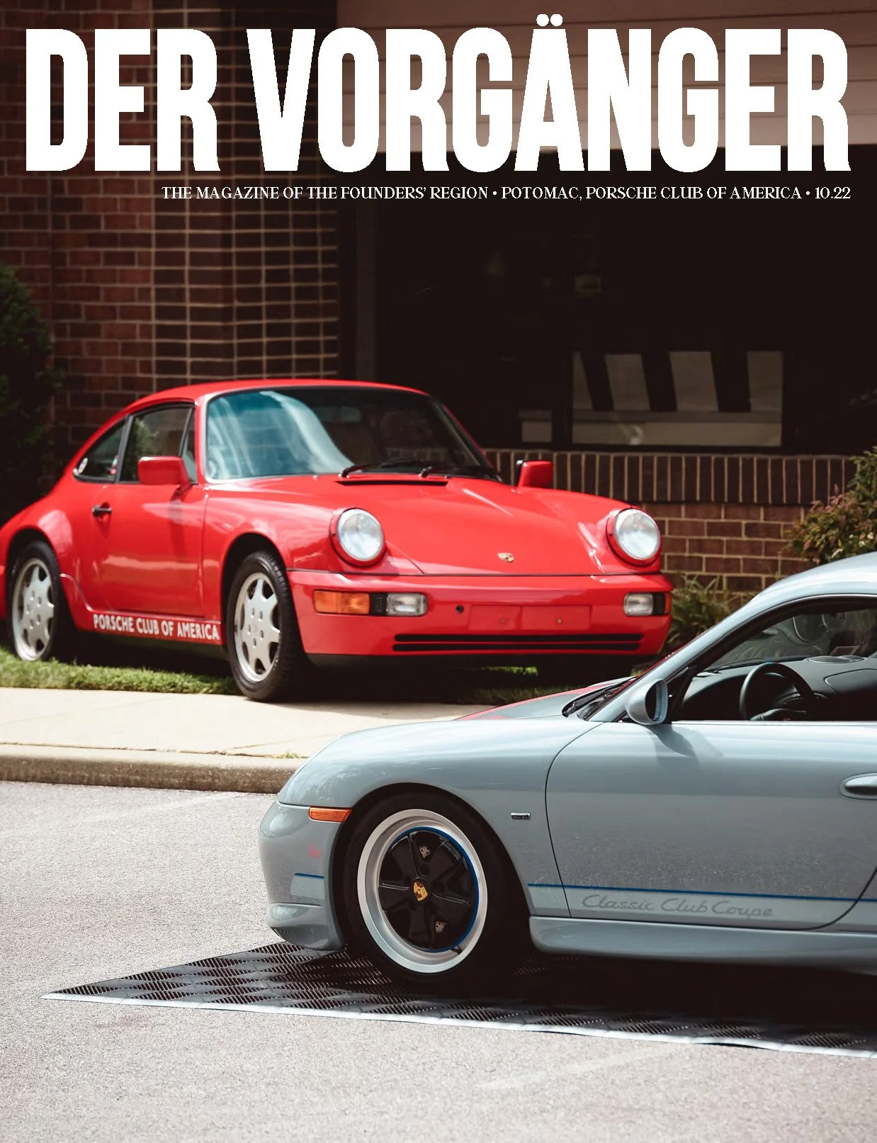 Image of two Porsche sports cars, one red parked on the driveway and one silver on the street, with a brick building in the background.