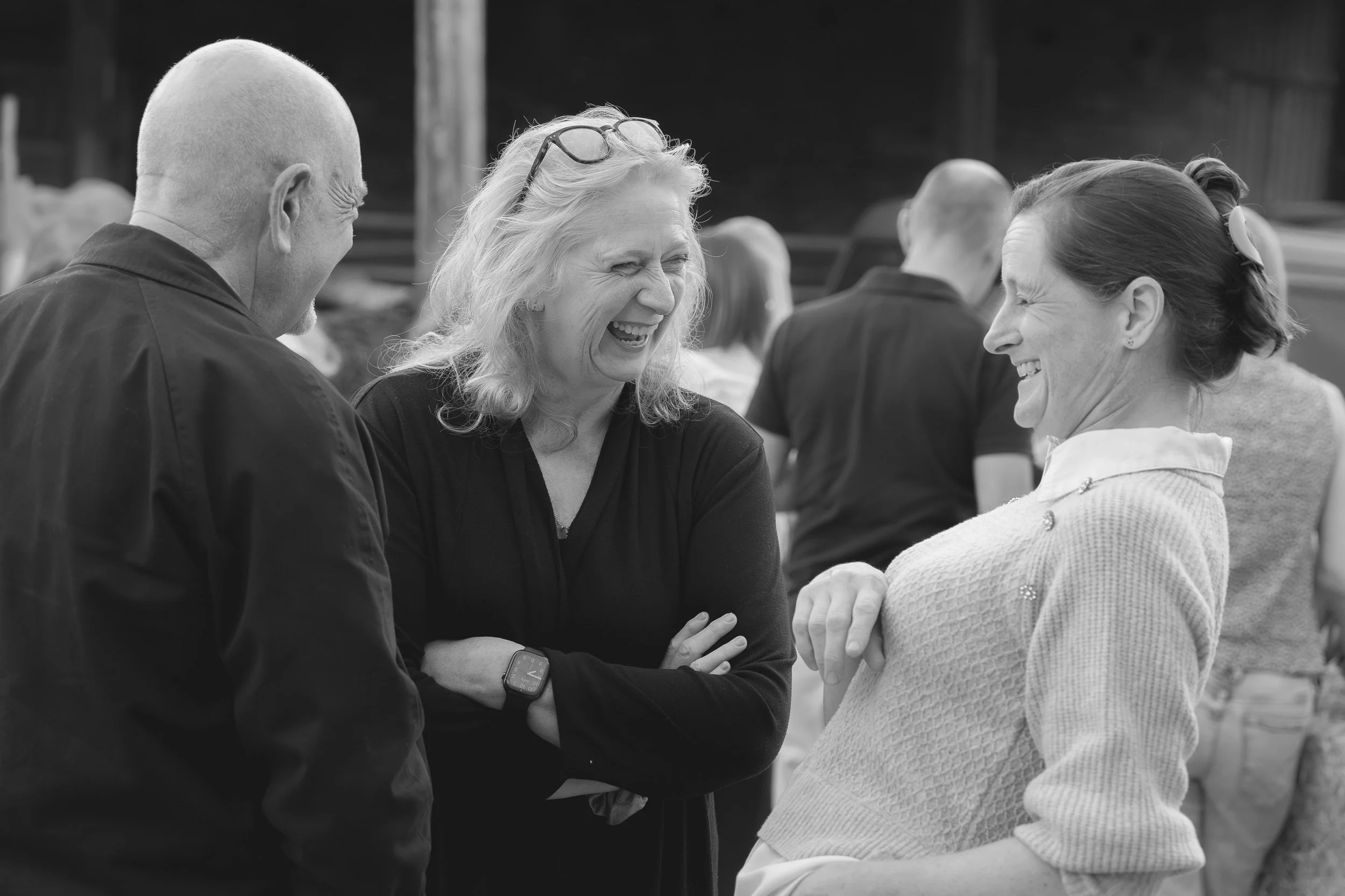 Three people, two women and one man, are engaged in conversation outdoors. They are smiling and appear to be enjoying each other's company.