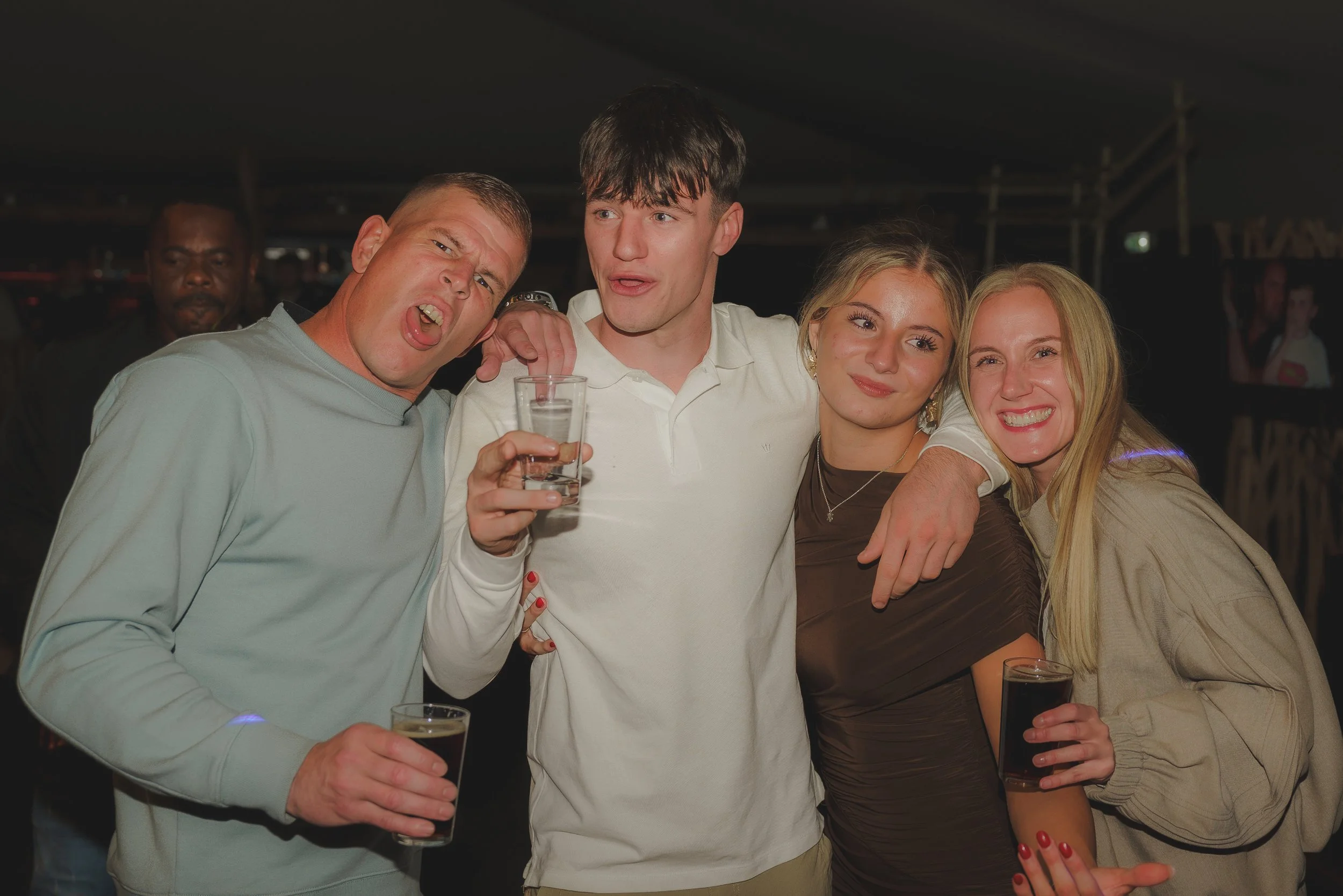 Group of friends celebrating with drinks at a social event, smiling and posing for the camera.