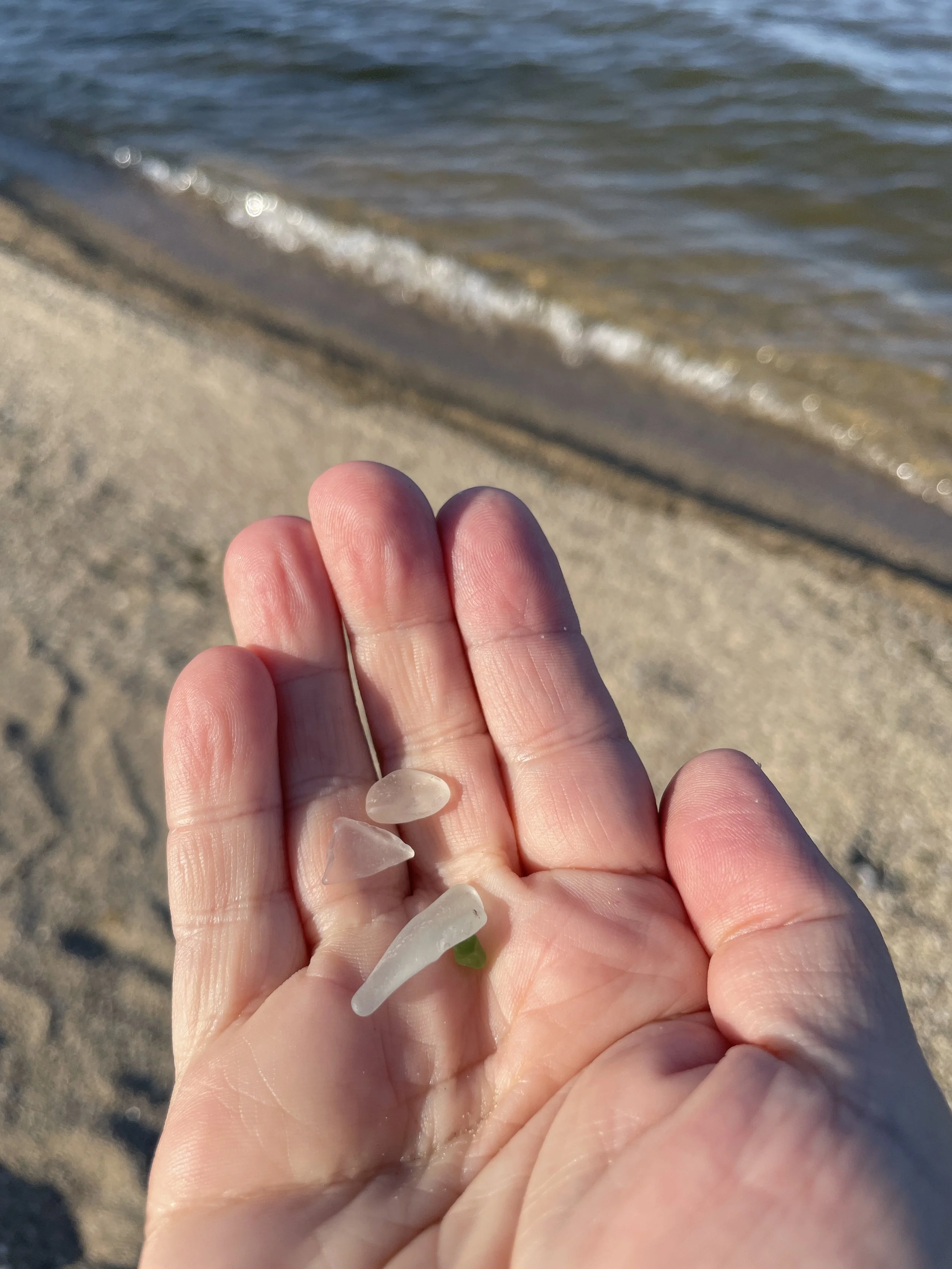 Hand reaching out holding beach glassn the light