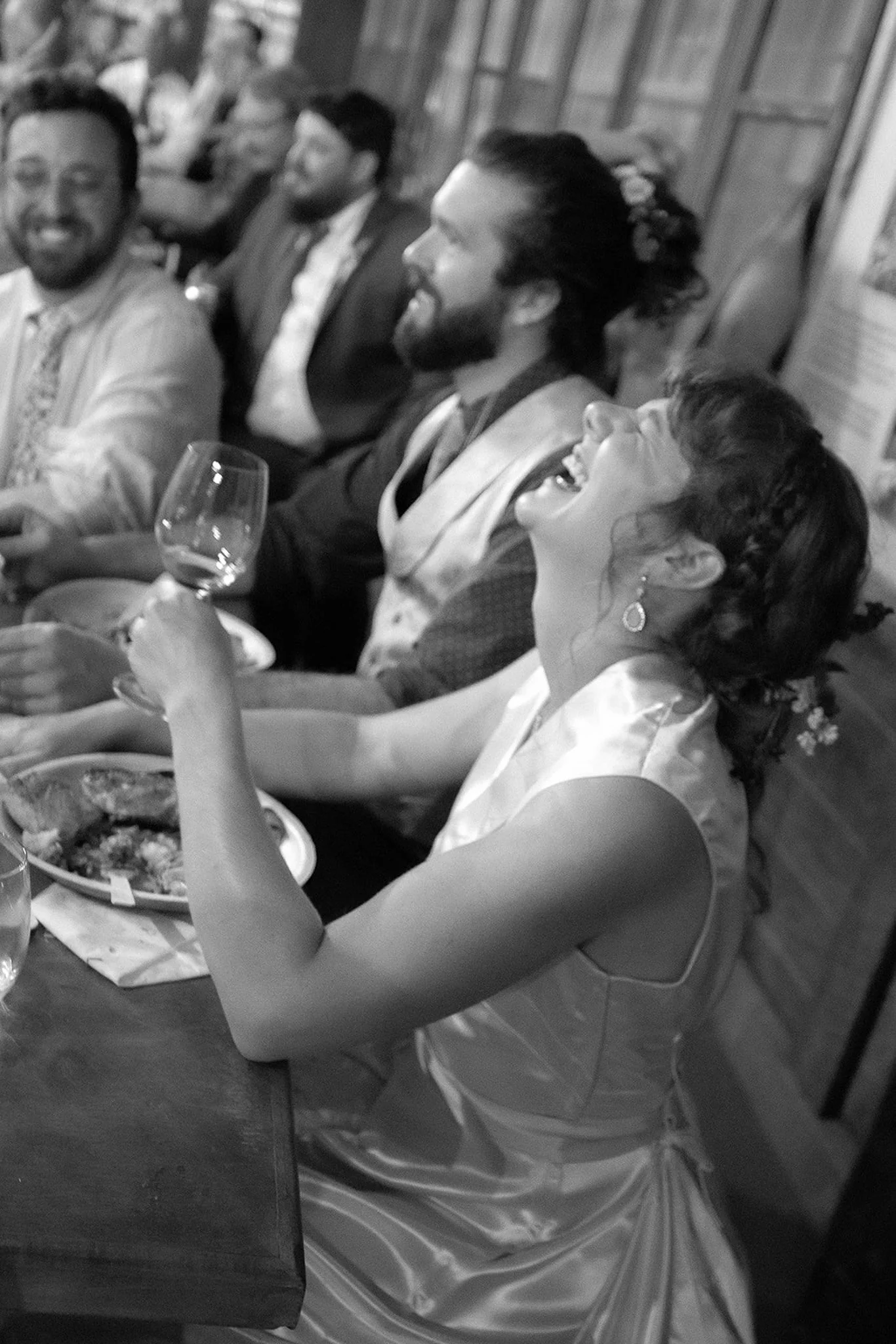 People sitting around a dining table, enjoying a meal and laughing.