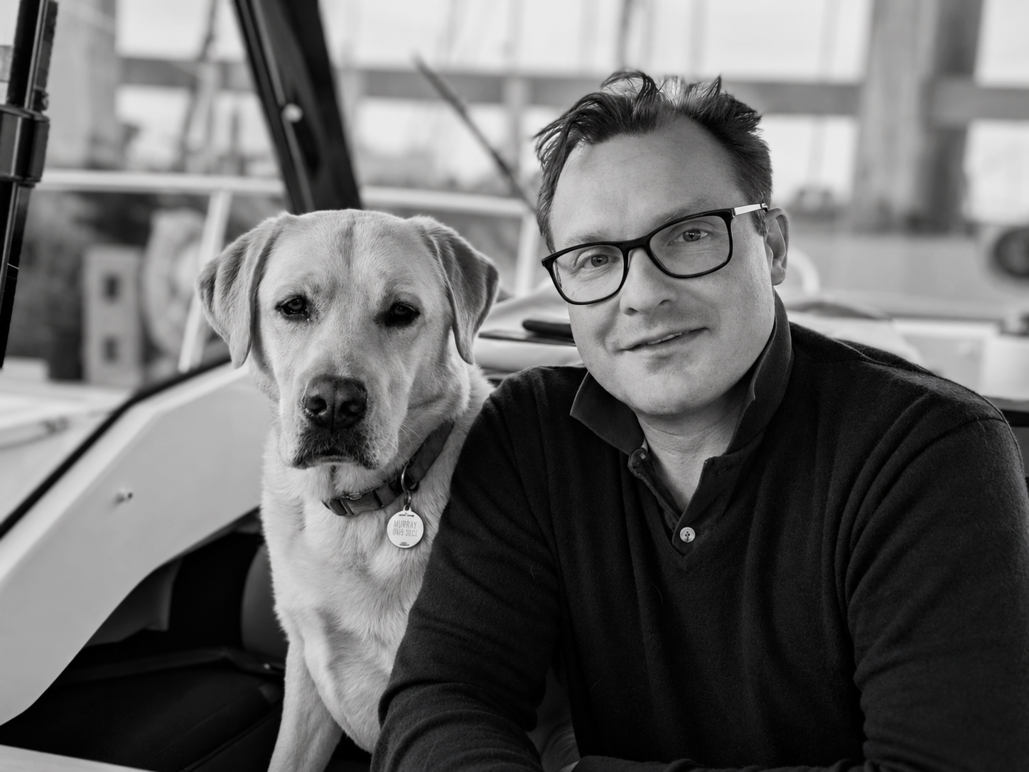Black-and-white portrait of Ben Dodd, SOLGLØD founder, sitting beside his Labrador Retriever, Murray.