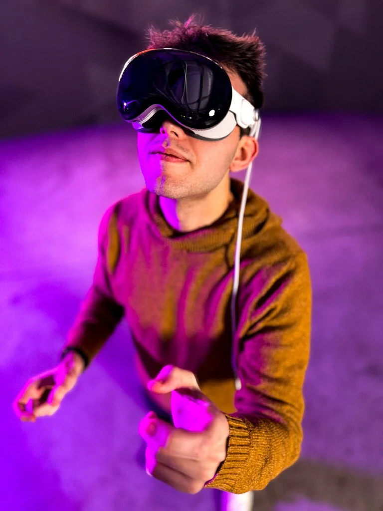 Man wearing a virtual reality headset and holding motion controllers under purple lighting