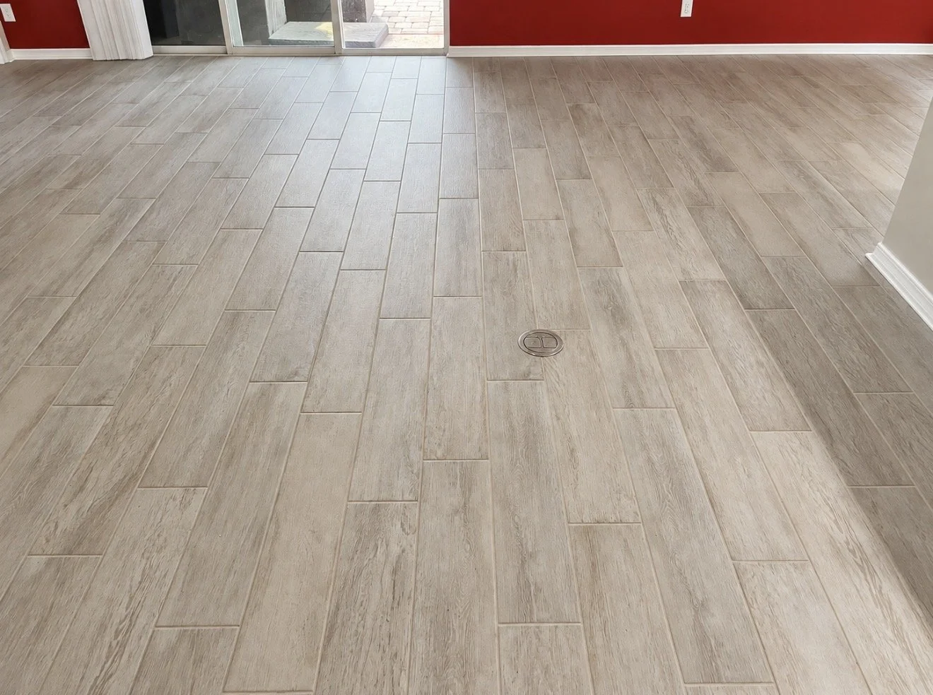 Professional installation of light wood-look plank flooring with a staggered tile pattern and natural wood-grain finish.
