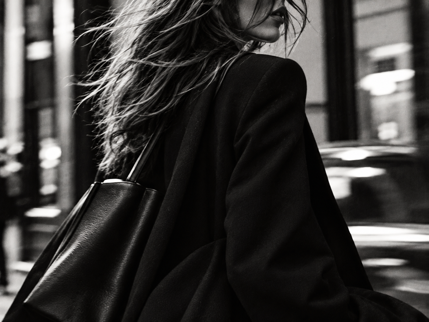 Woman walking in  the city with blazer and bag.