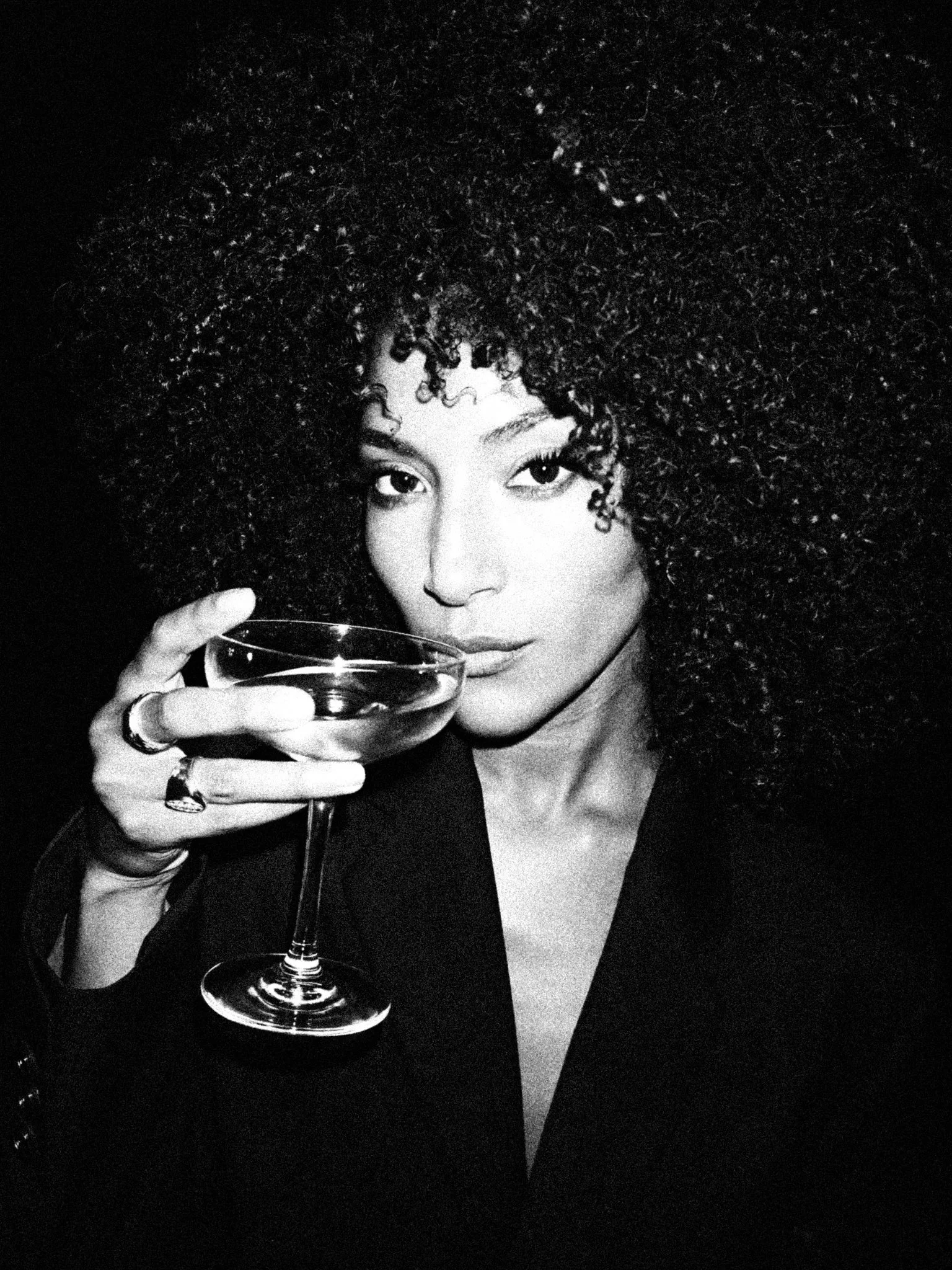 Black and white image of a woman drinking a cocktail.