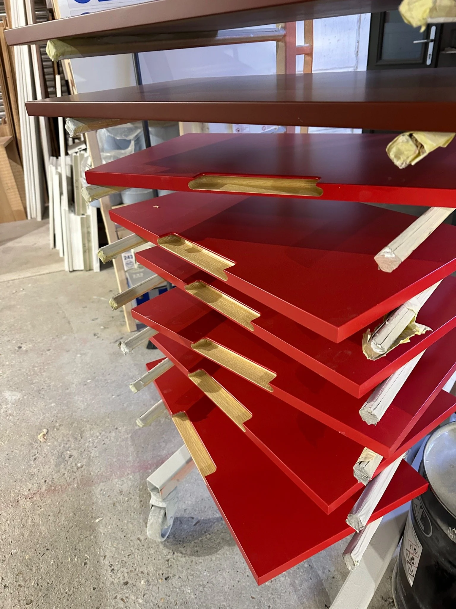 Two-colour cabinet finishing — red sprayed fronts with contrasting natural wood handle details by Kemispray in Brentford.