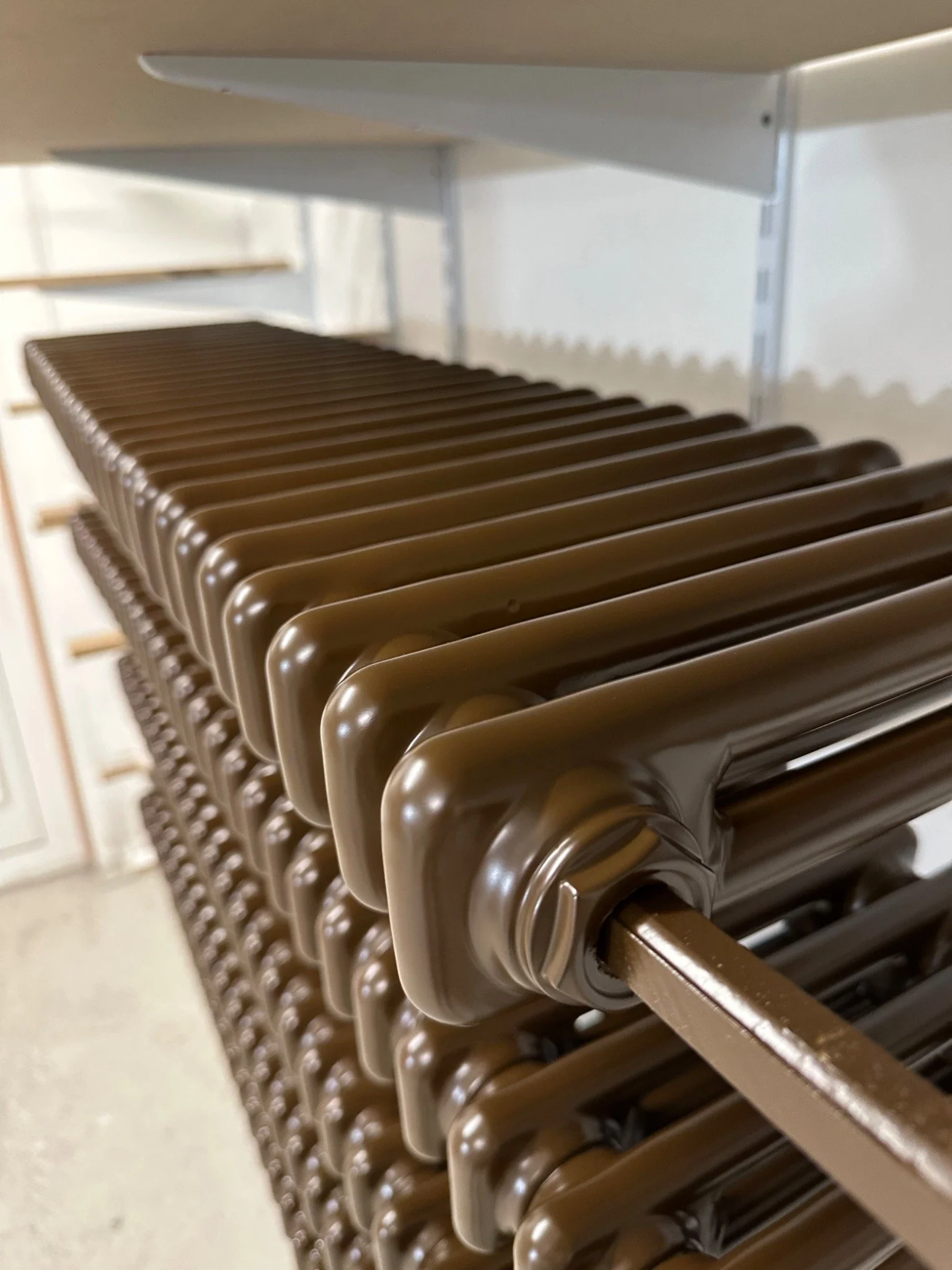 Radiator spray painting — brown finish on column radiators at the Kemispray workshop in Brentford, West London.