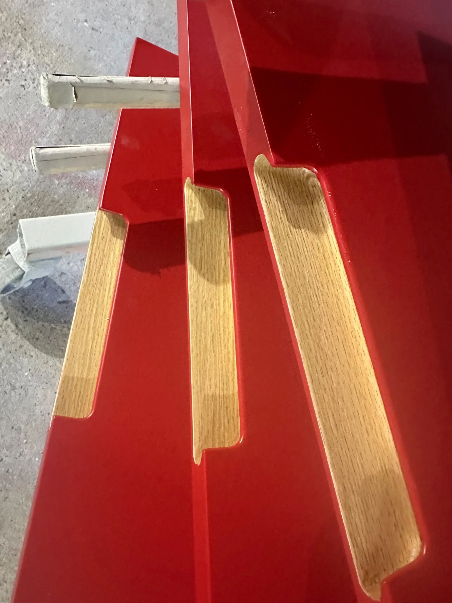 Two-colour furniture & cabinet fronts — red sprayed surfaces with contrasting natural wood handle details. Kemispray, Brentford.