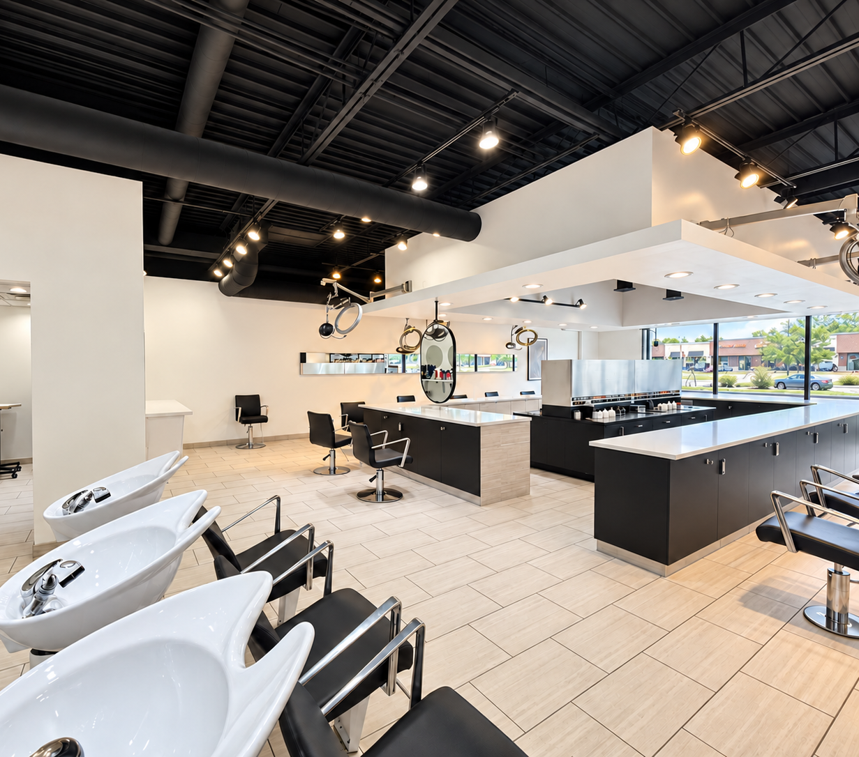 Modern hair salon interior with washing stations, styling chairs, mirrors, large windows, and hanging hair dryers.
