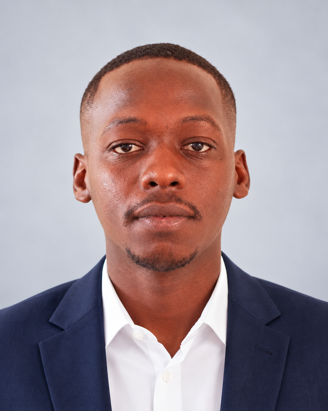 A portrait of a young man in formal business attire, wearing a navy blazer and white shirt, against a light gray background.