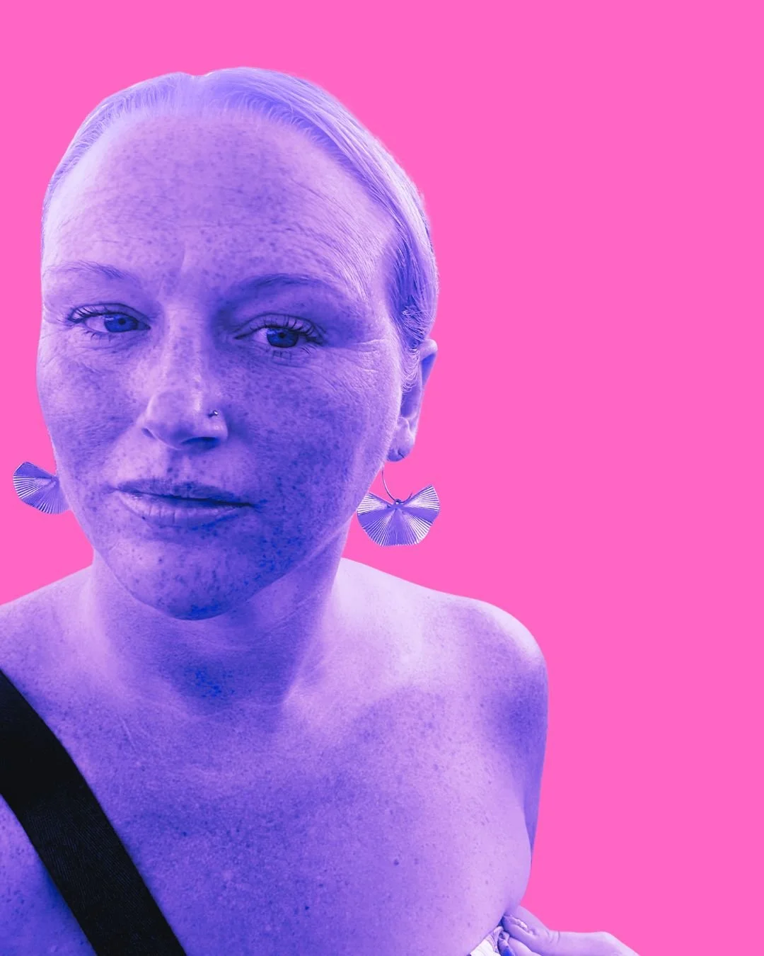 Close-up portrait of a woman with fair skin and blue eyes, wearing large fan-shaped earrings. The background is pink, and her face and shoulders are tinted purple, giving a stylized, artistic effect.