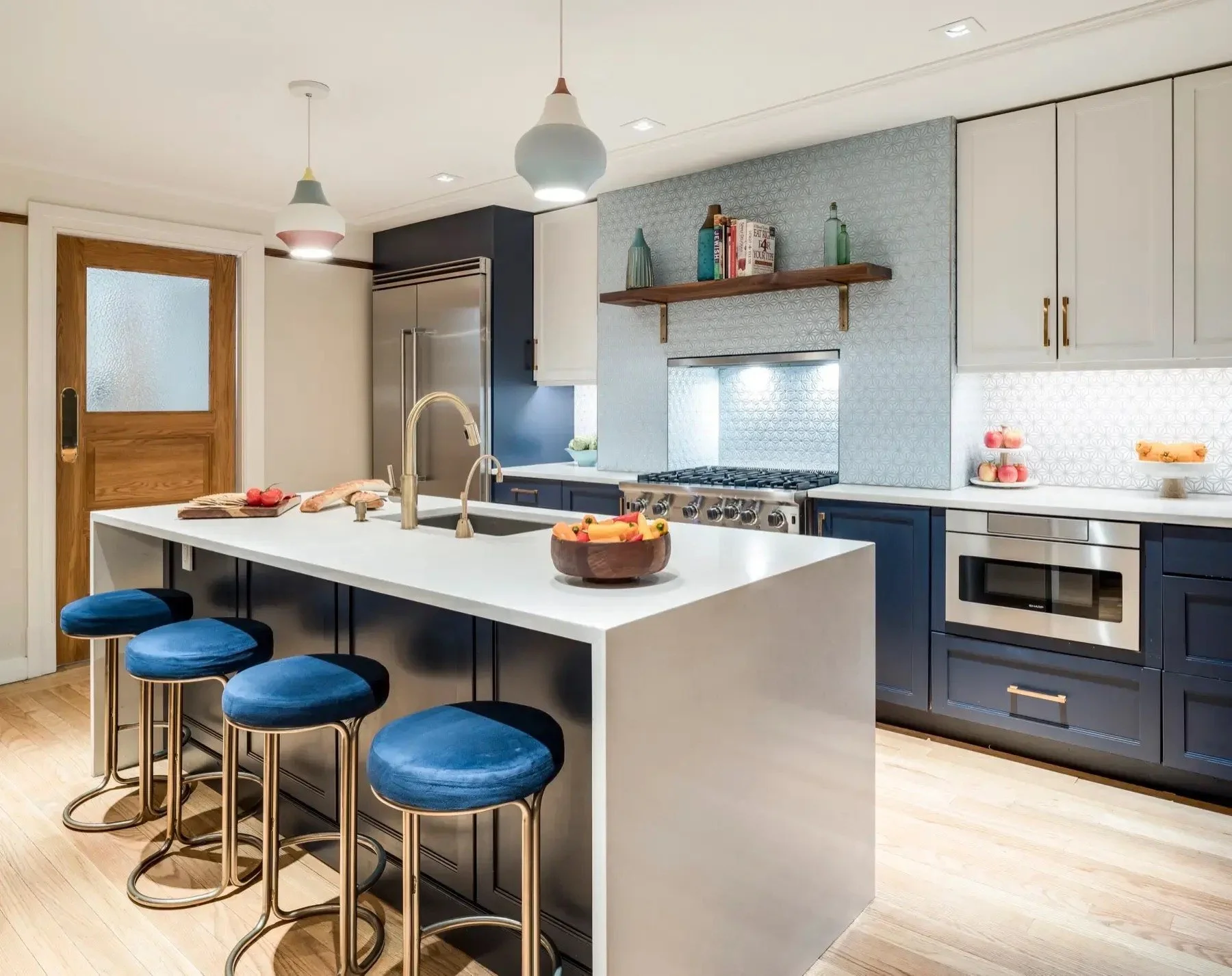 West 138th Street brownstone kitchen with pale cabinetry, a generous island, blue upholstered stools and warm wood accents.