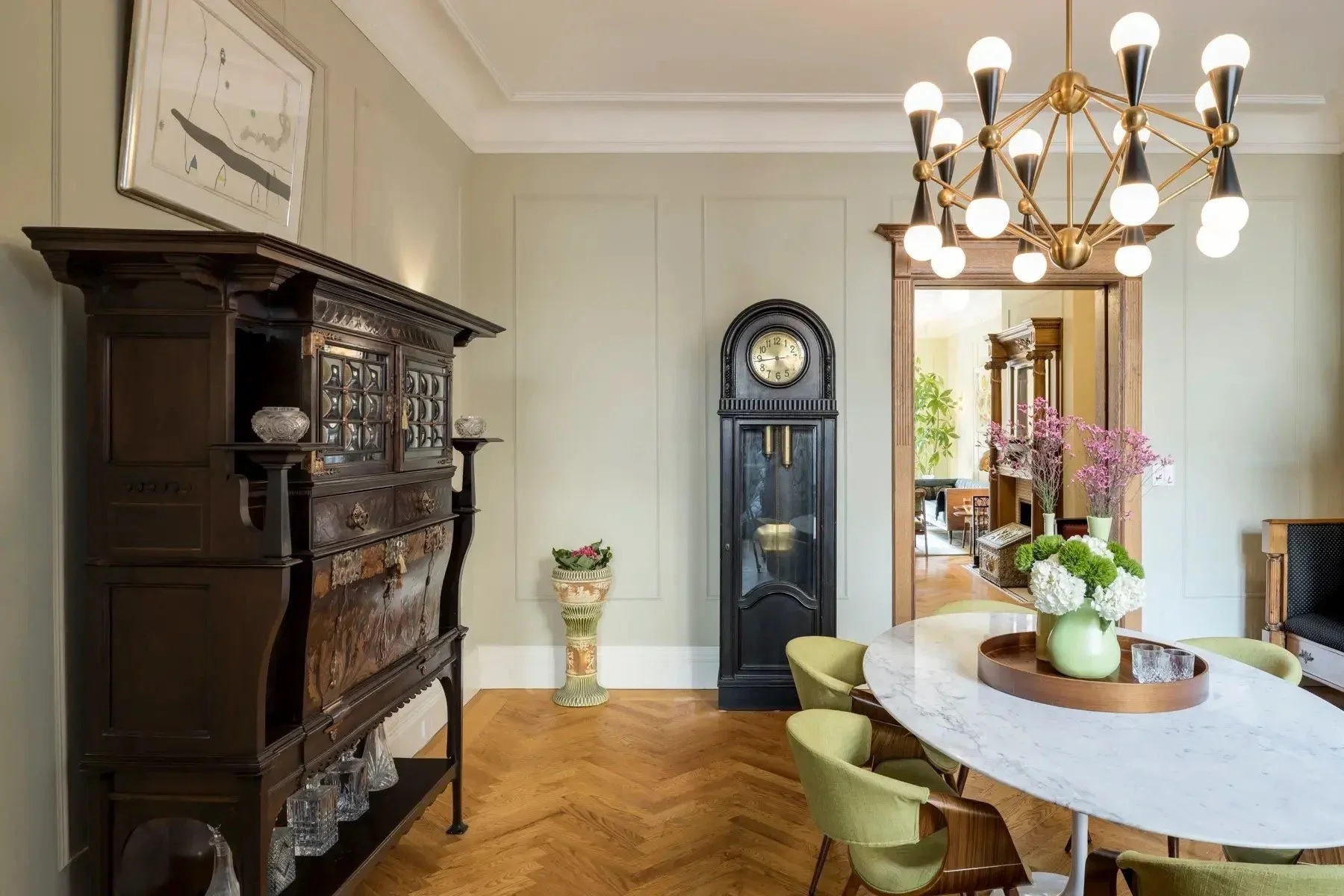 West 138th Street brownstone dining room with period woodwork, a round dining table and sculptural contemporary lighting.
