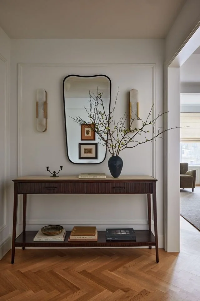 Entry vignette with sculptural mirror, console and thoughtfully arranged objects.