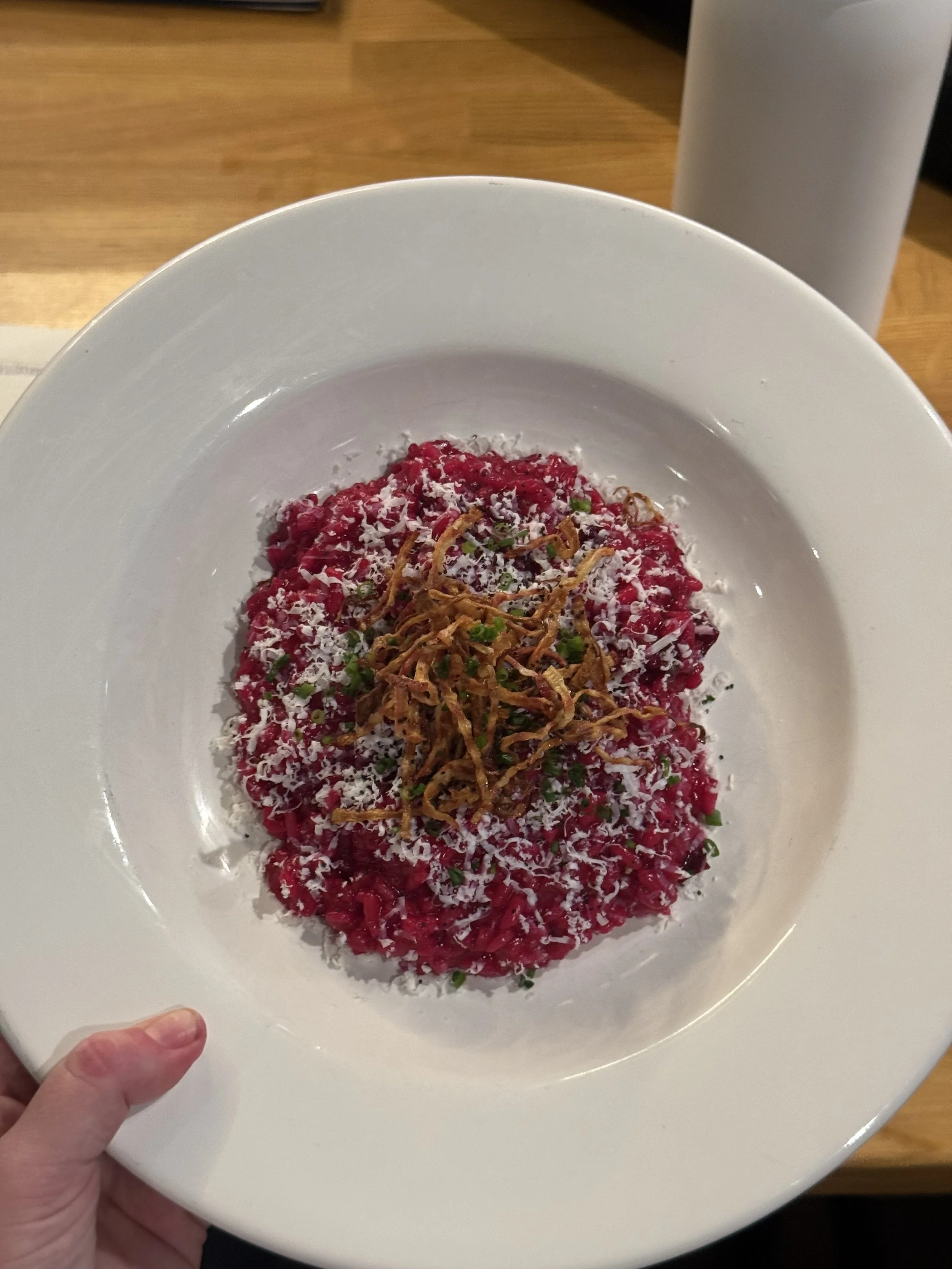 A plated beet salad topped with shredded cheese, scallions, and crispy fried onions.