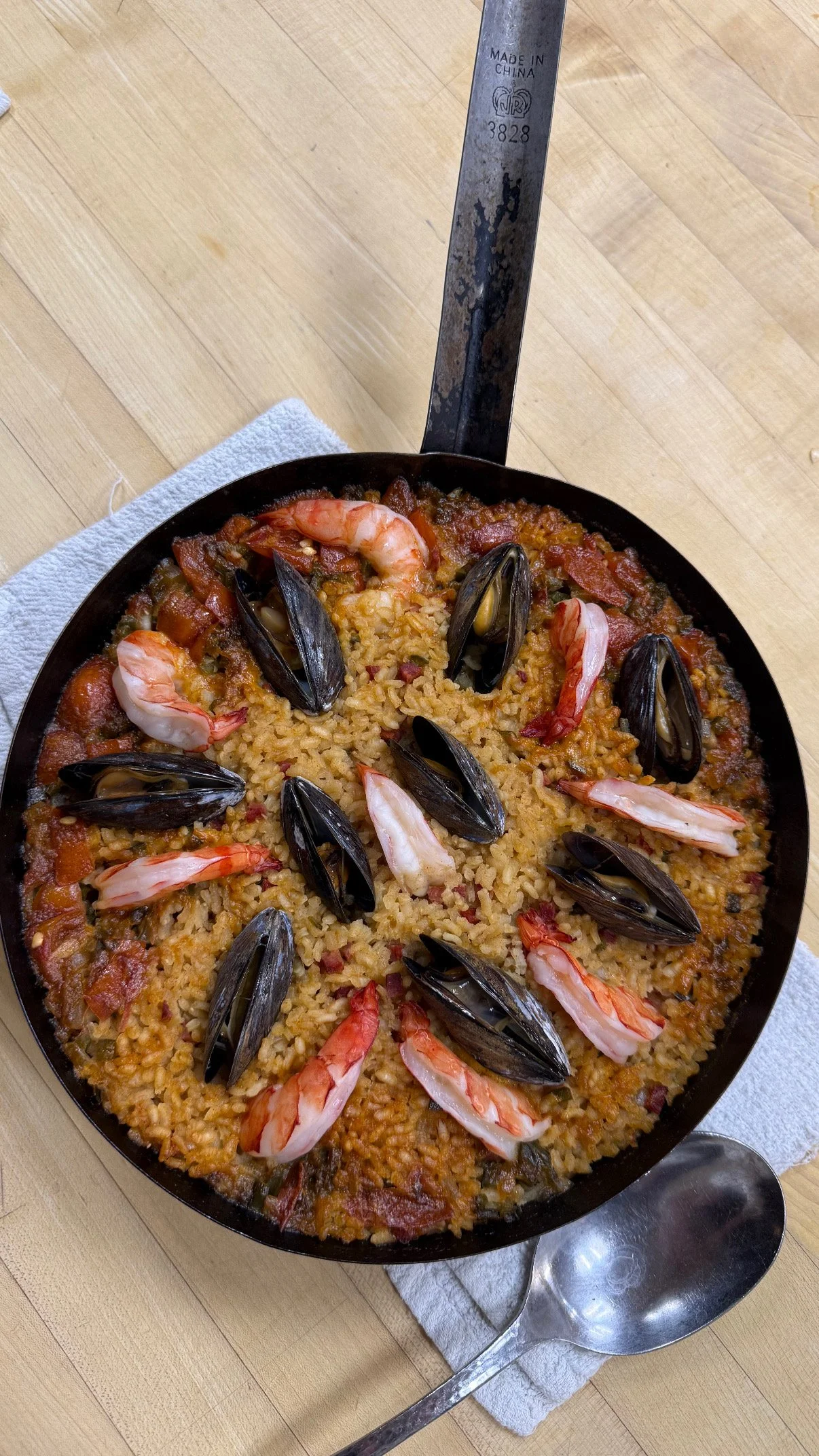 Seafood paella with shrimp and mussels in a black skillet.