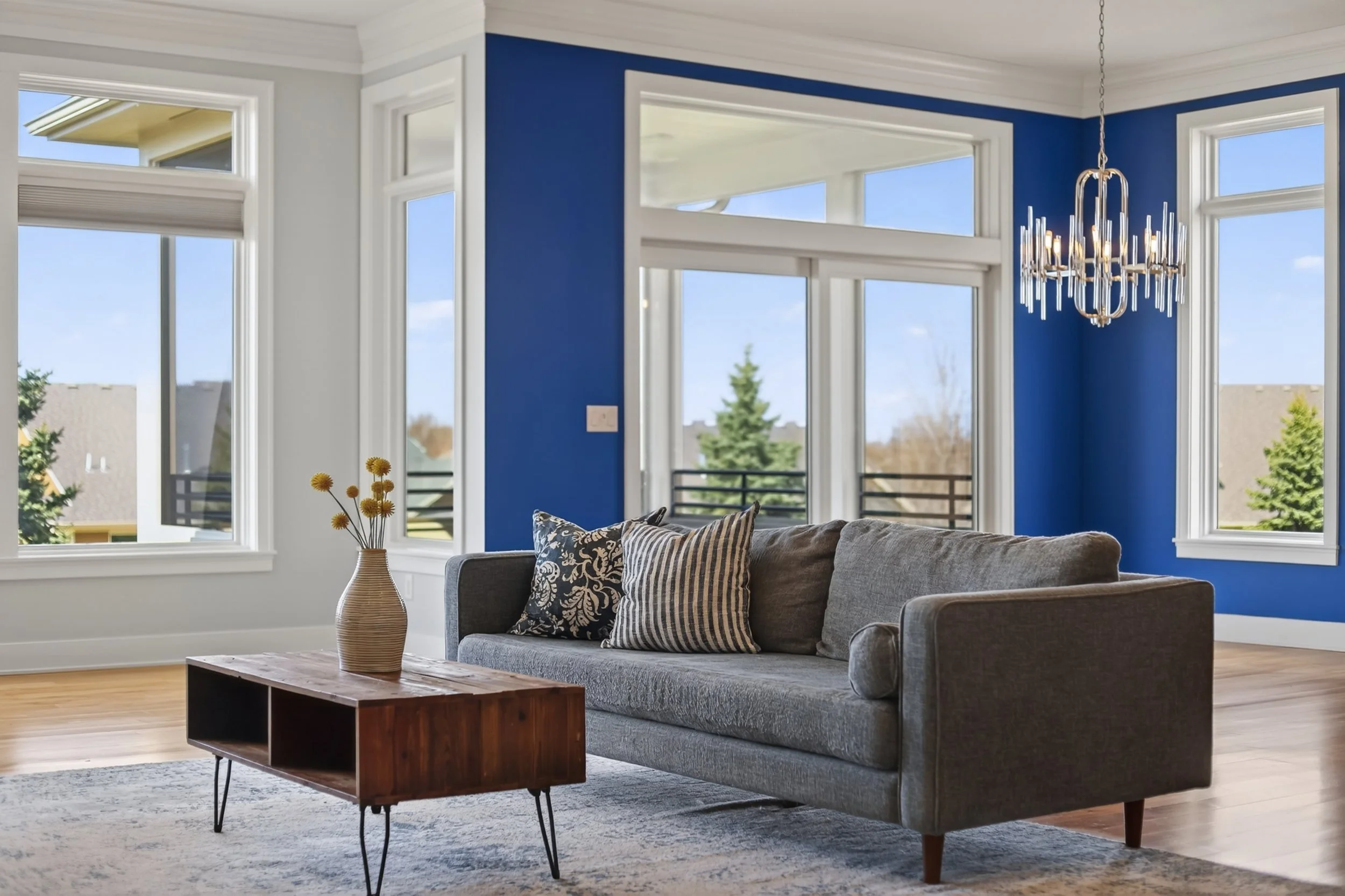 Living room with cobalt walls, modern chandelier and large windows