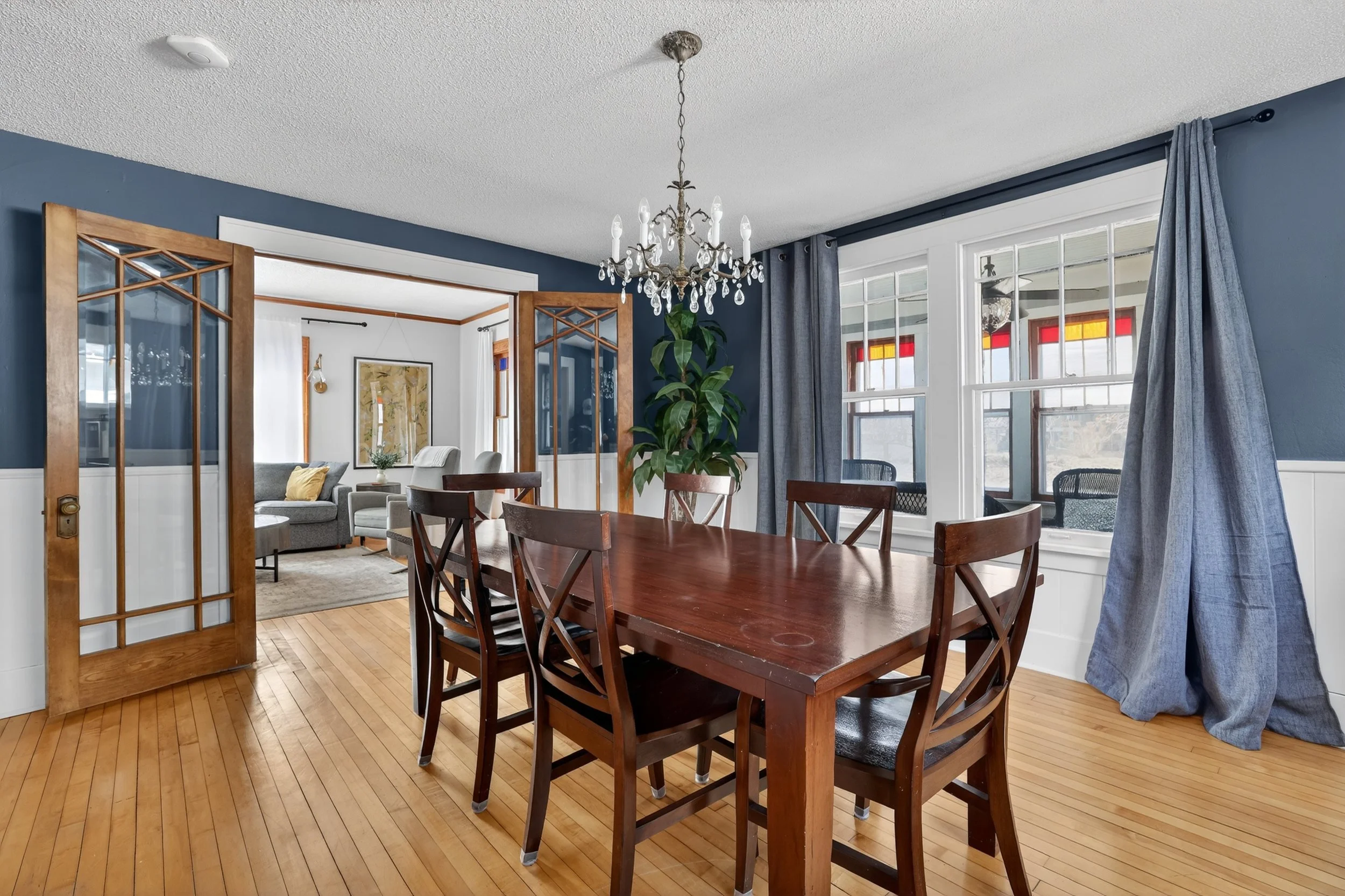 Dining room with navy walls, crystal chandelier and glass French doors