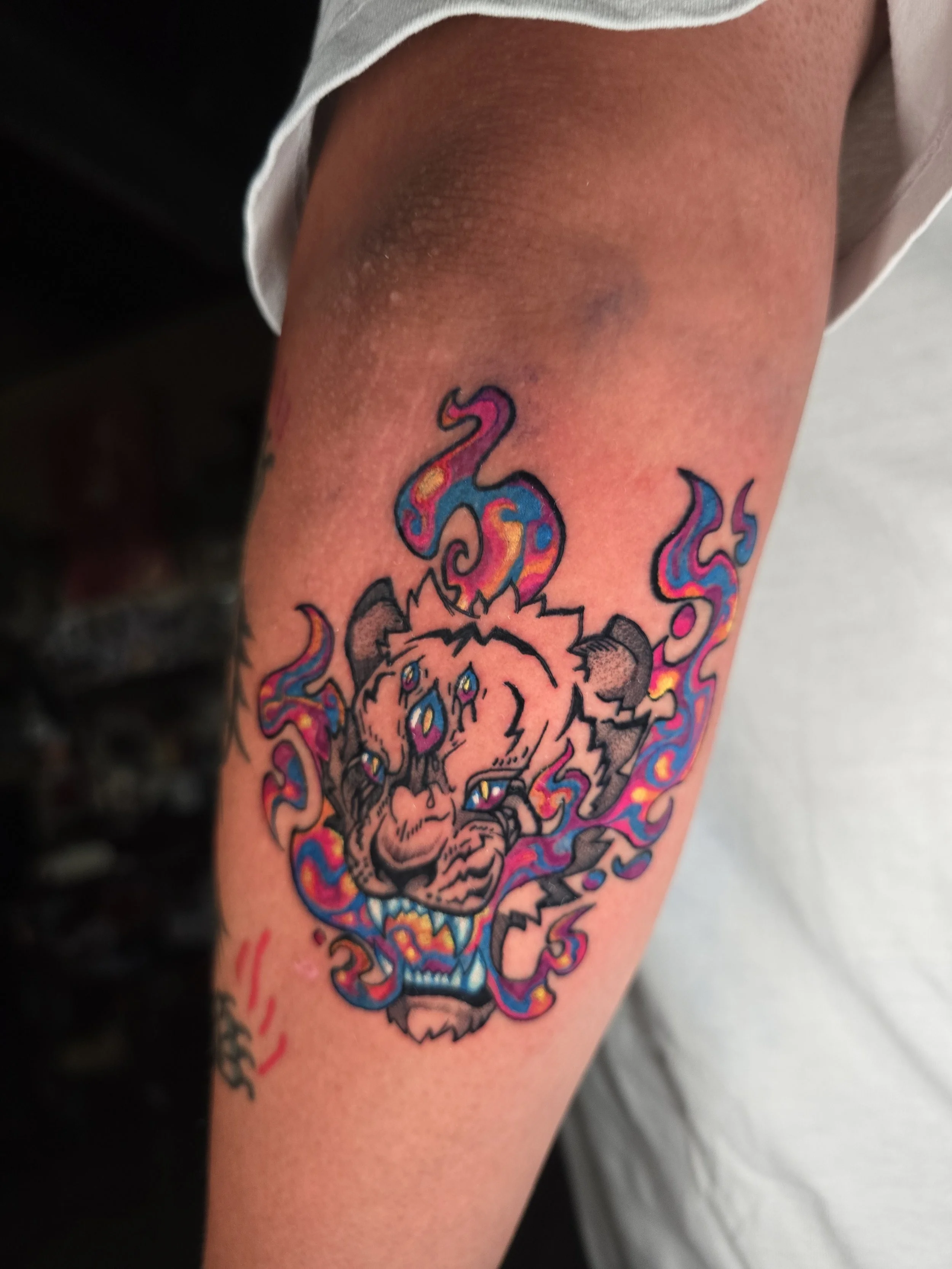 Colorful tattoo of a skull with tentacles on upper arm.
