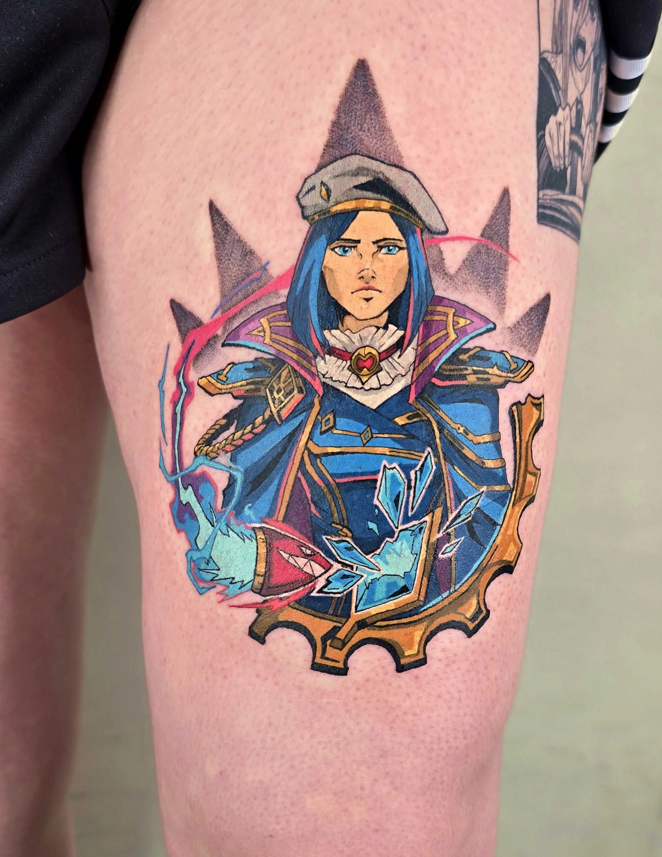 Tattoo of a female character with blue hair in a military-style uniform, wearing a gray hat, surrounded by a gear and lightning symbols.