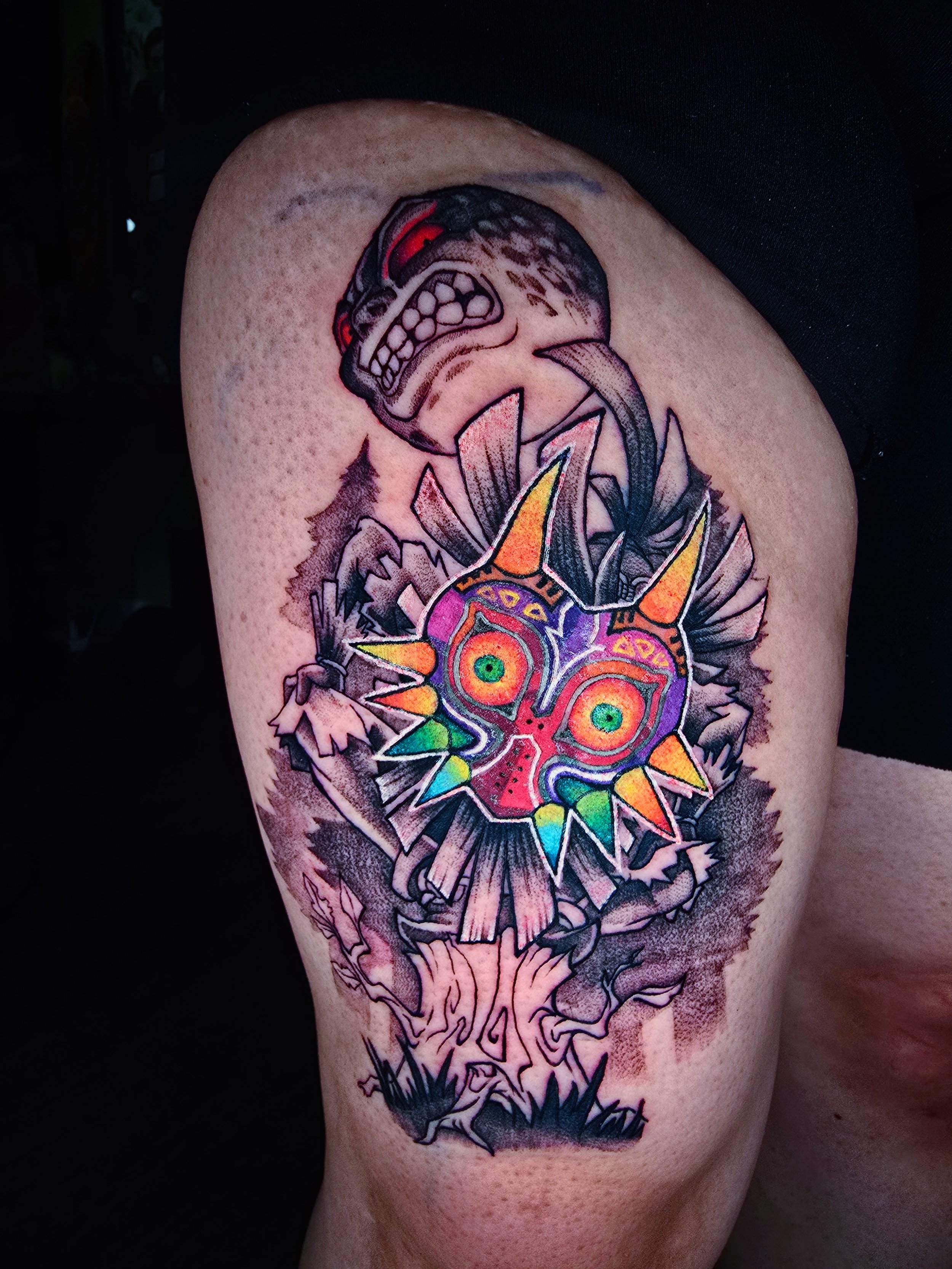 Tattoo of a cartoonish dragon head with a colorful explosion design on its face, on a person's upper arm.