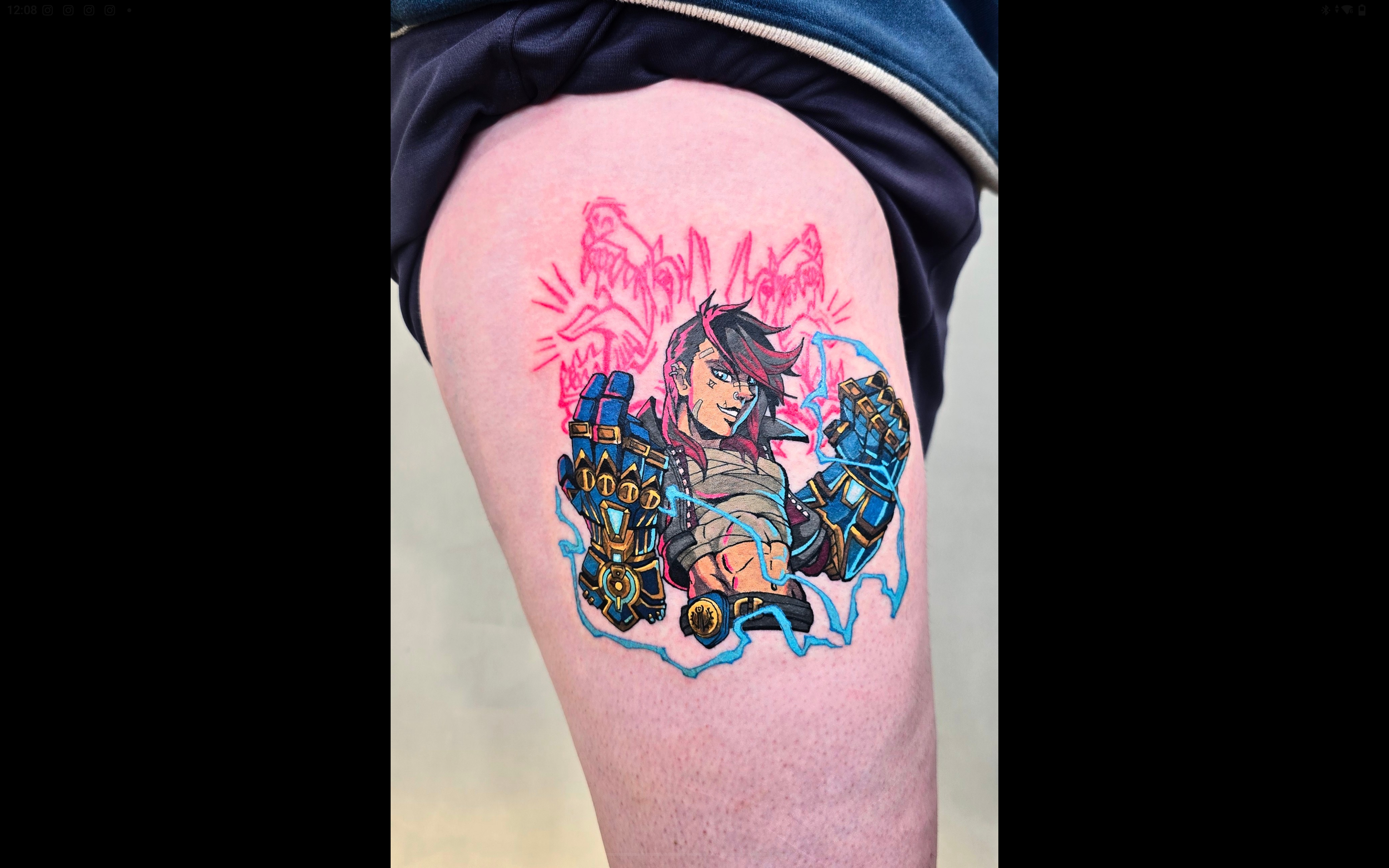 Colorful tattoo of a video game character with long dark hair, armored gloves, and a confident expression on the upper arm of a person in a dark shirt.