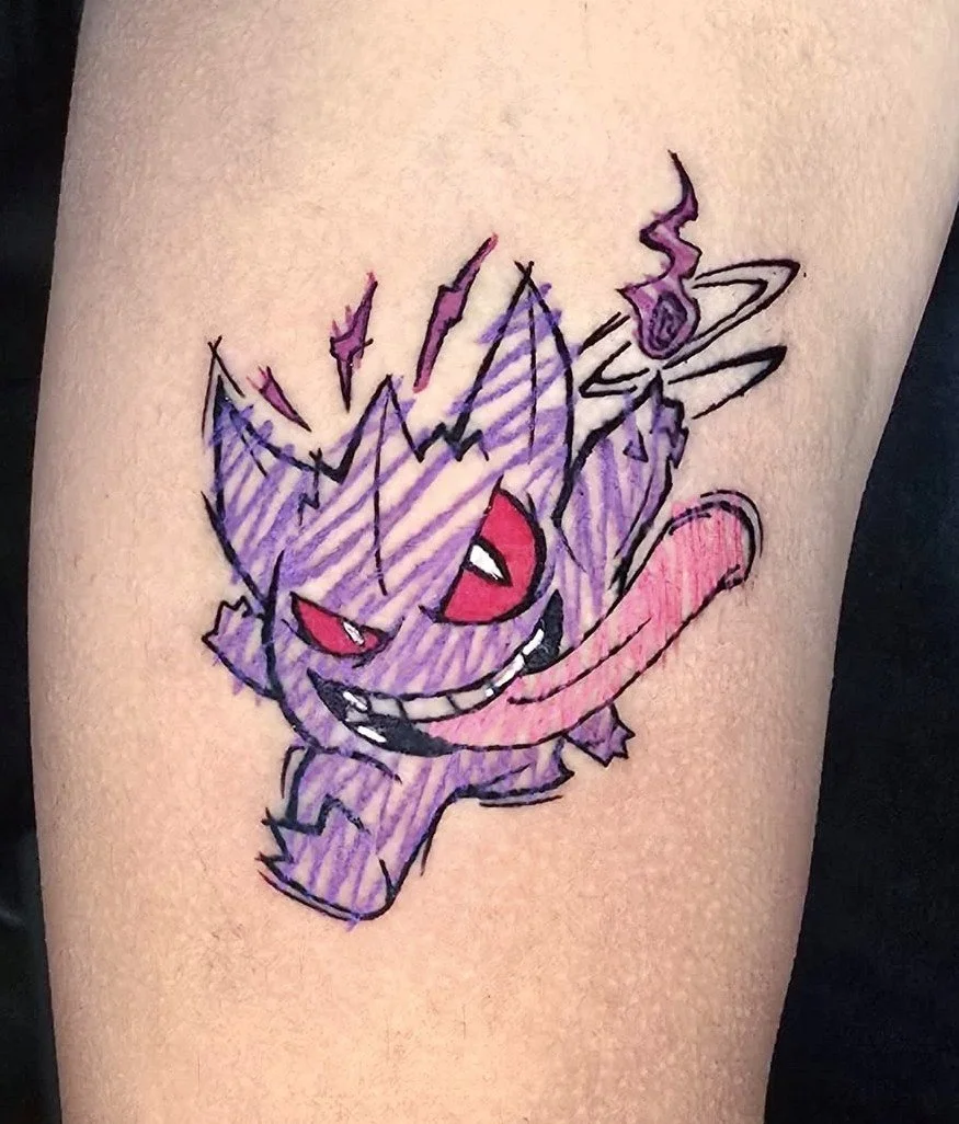 Colorful tattoo of a mischievous, purple cartoon character with red eyes, sharp teeth, and a long pink tongue, holding a smoking pipe.