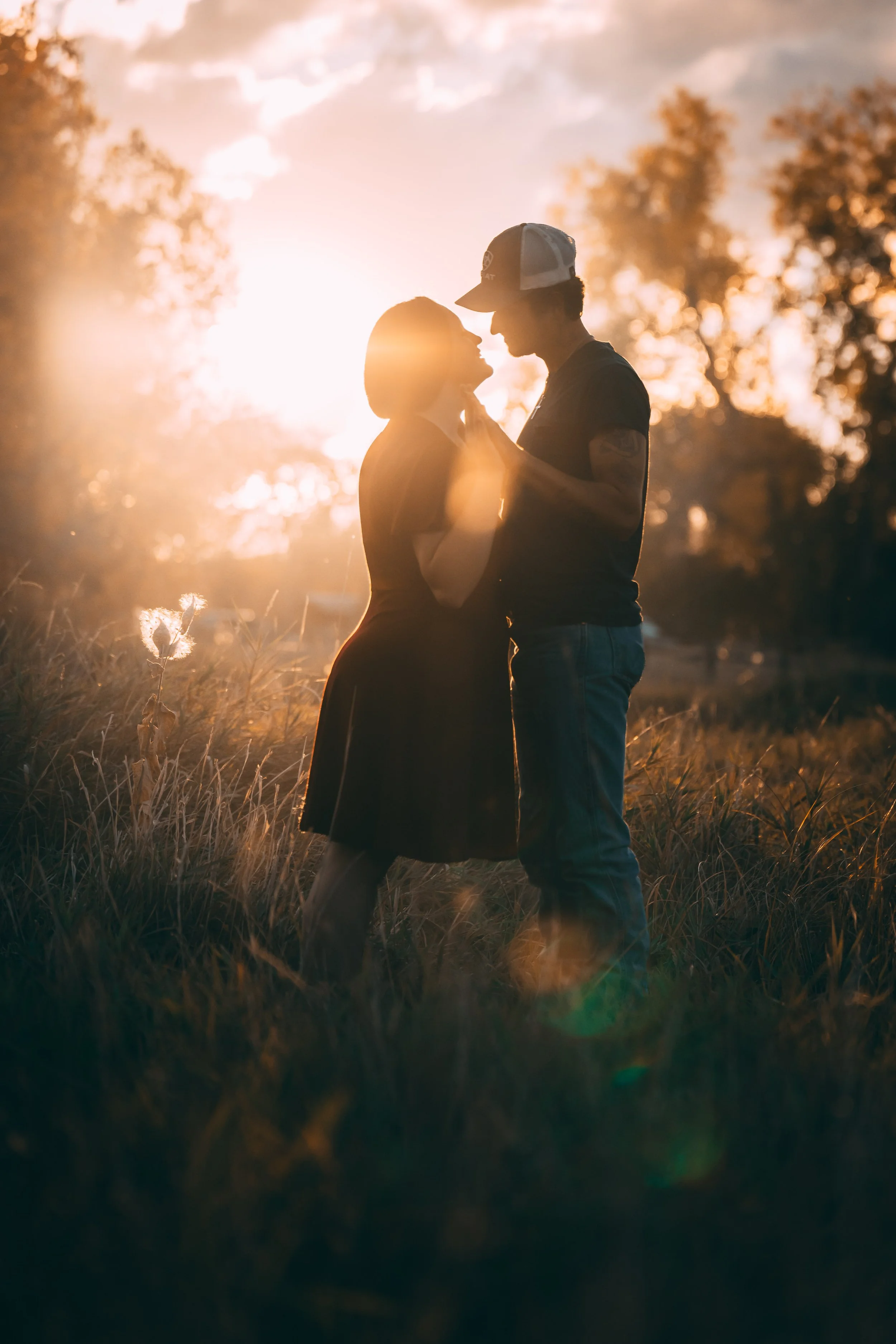 Silhouetted couple embracing in a sunlit field at sunset