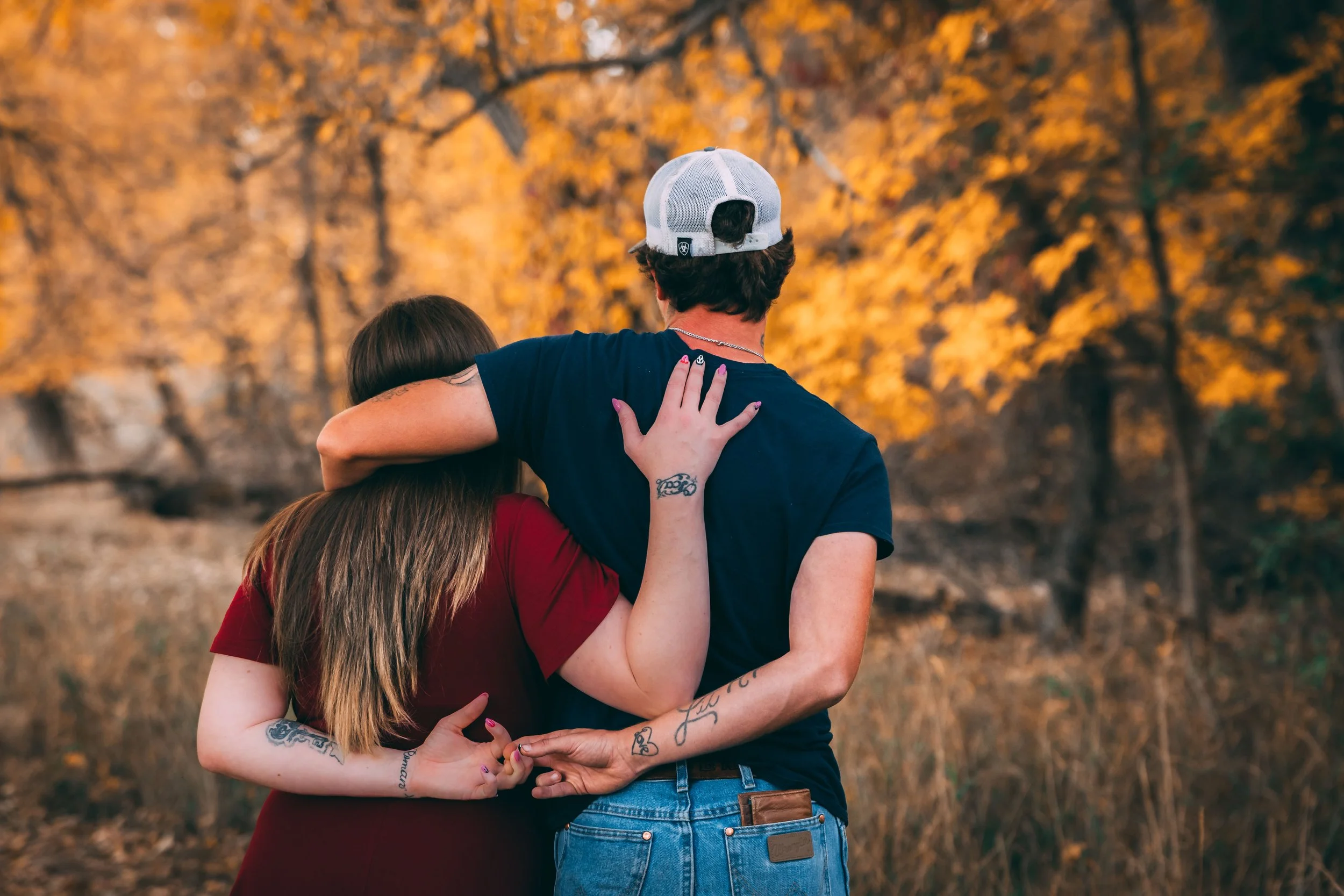 Three friends embracing in an autumn forest with golden foliage