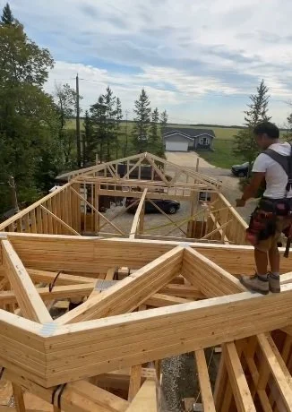 Construction worker standing on newly installed wooden roof trusses of a house under construction