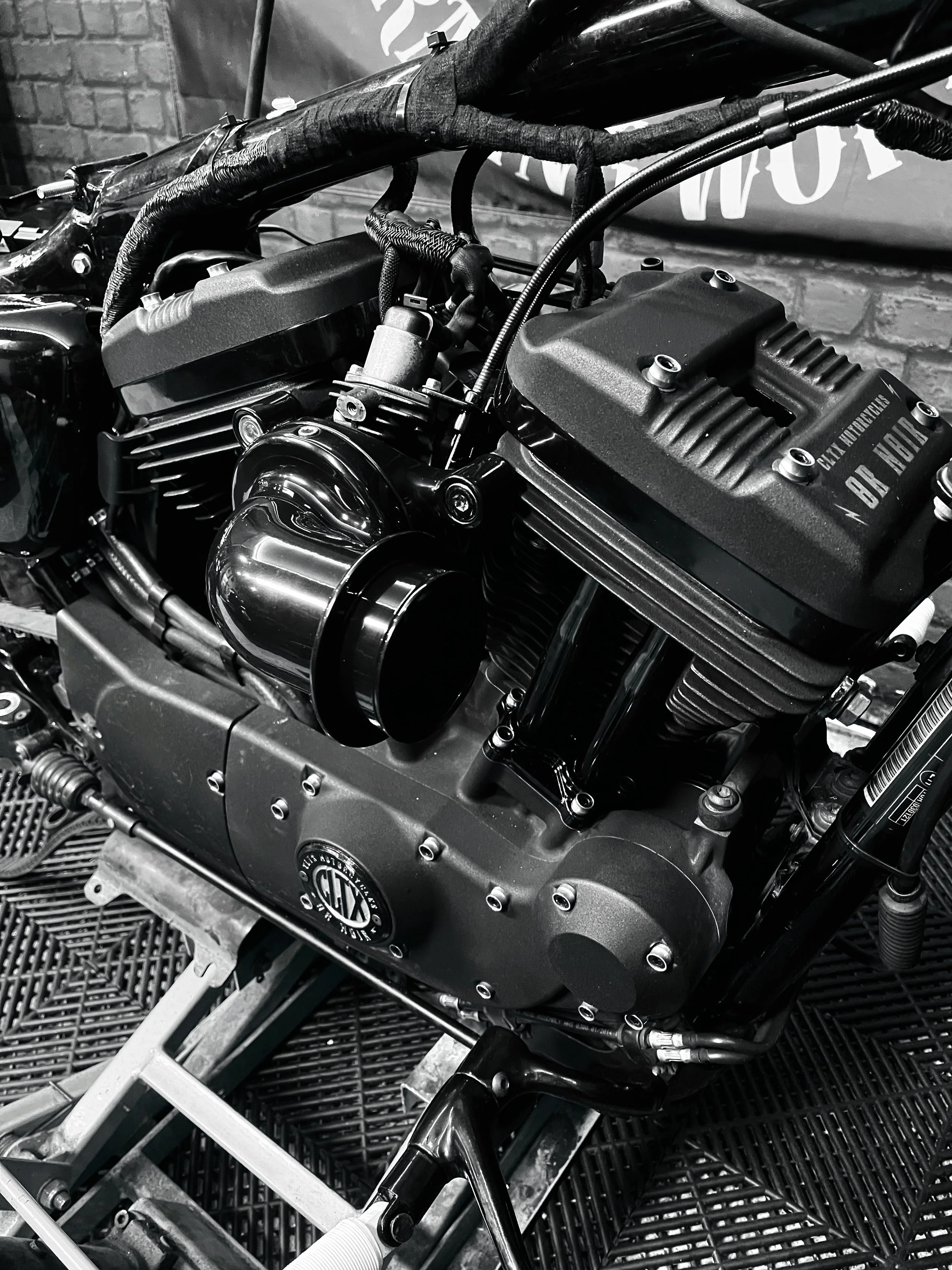 Un moteur de moto avec des détails métalliques et des composants mécaniques visibles, photo en noir et blanc.
