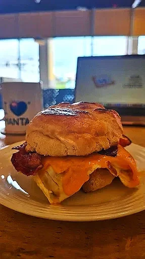 Un sándwich con pollo, tocino, queso y pan en un plato en un café.