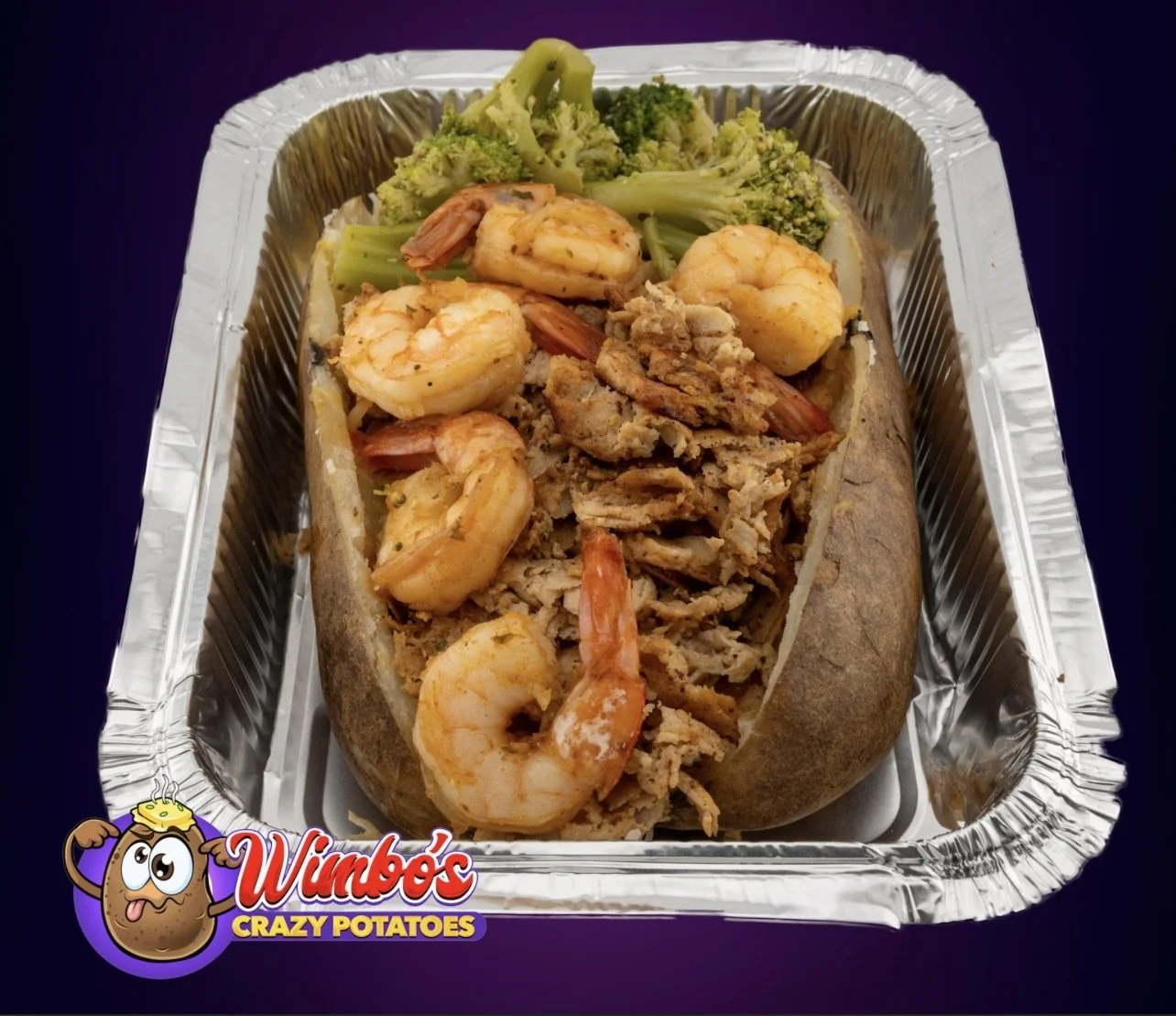 Loaded baked potato topped with shrimp, shredded chicken, broccoli, and mixed seasonings in aluminum tray.
