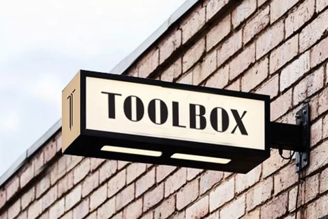An exterior sign made of sturdy metal with branding for Toolbox Men's Nail Salon.