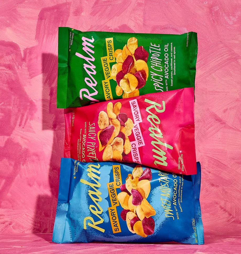 A stack of three flavors of Realm chips on a textured pink background.