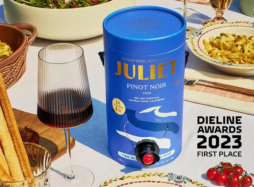 An ecomagnum(TM) container of Juliet Pinot Noir wine sits on an elegant tablescape outdoor dinner scene.