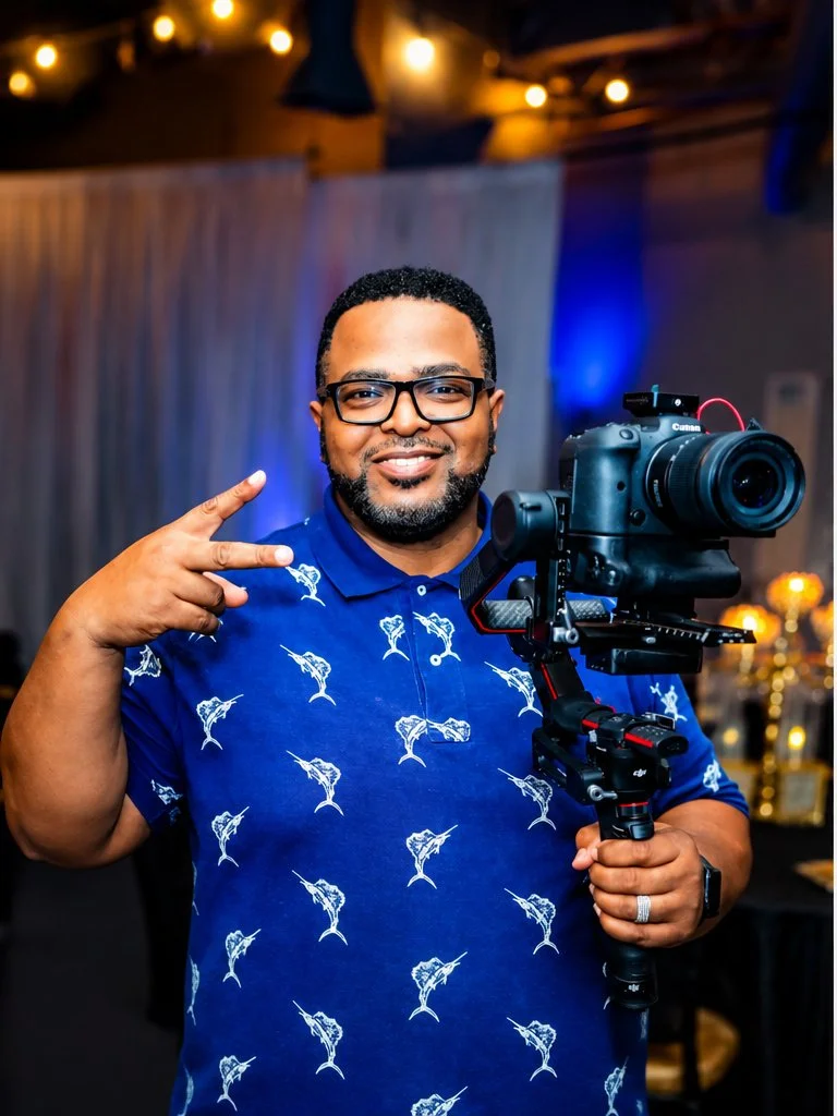 Willis Pugh in a blue polo holding his Canon camera and gimbal.