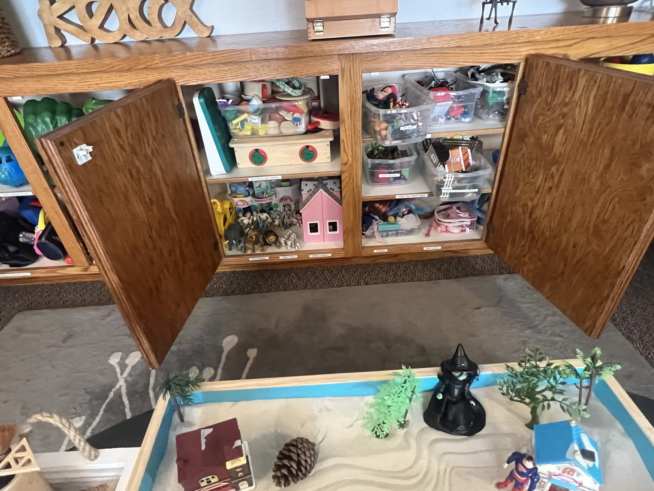 Play therapy room at Safe Harbor Counseling Center with open toy cabinets, dollhouses and a sand tray