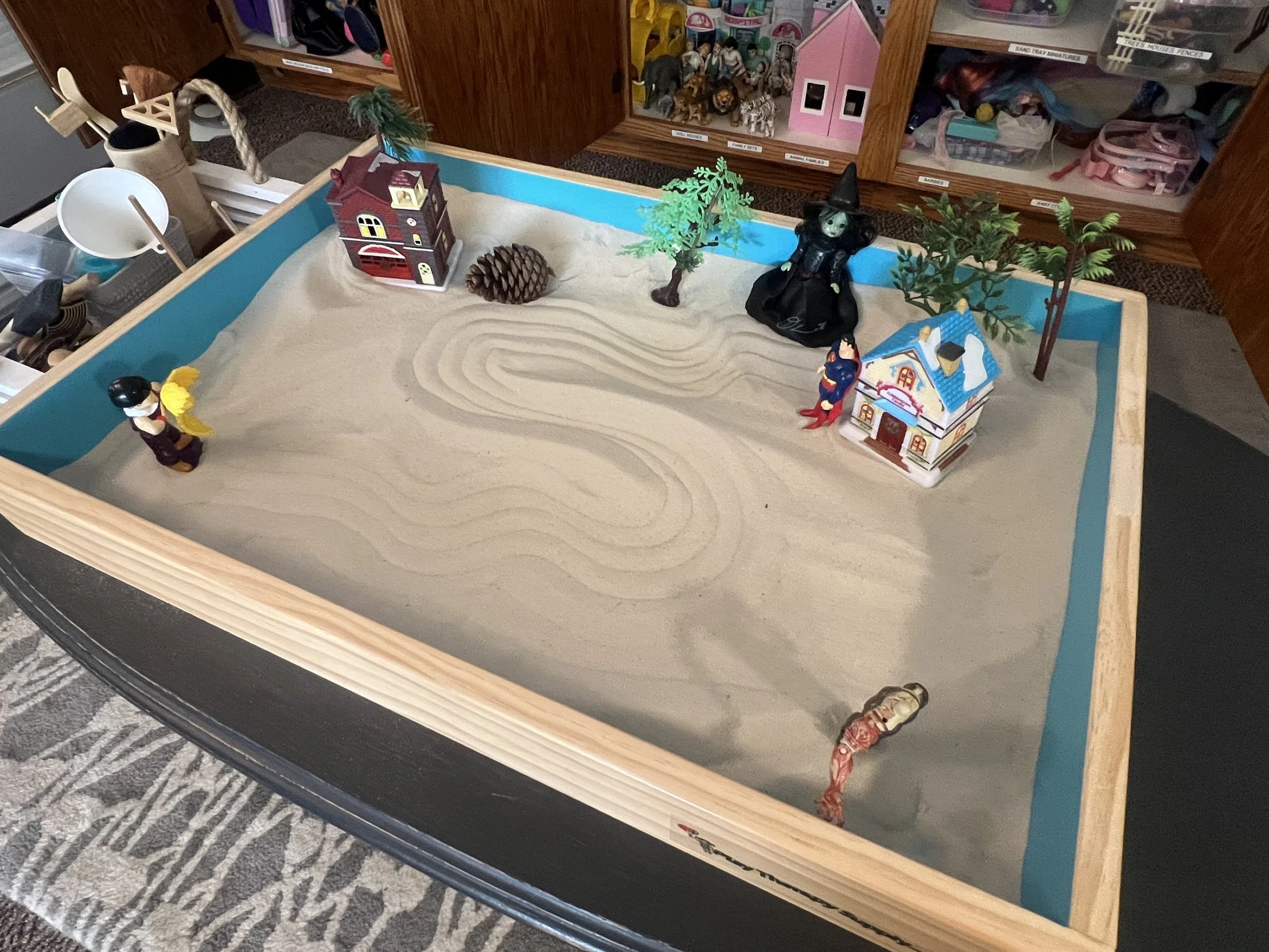 Sand tray with miniature houses, trees and figures in the play therapy room at Safe Harbor Counseling Center